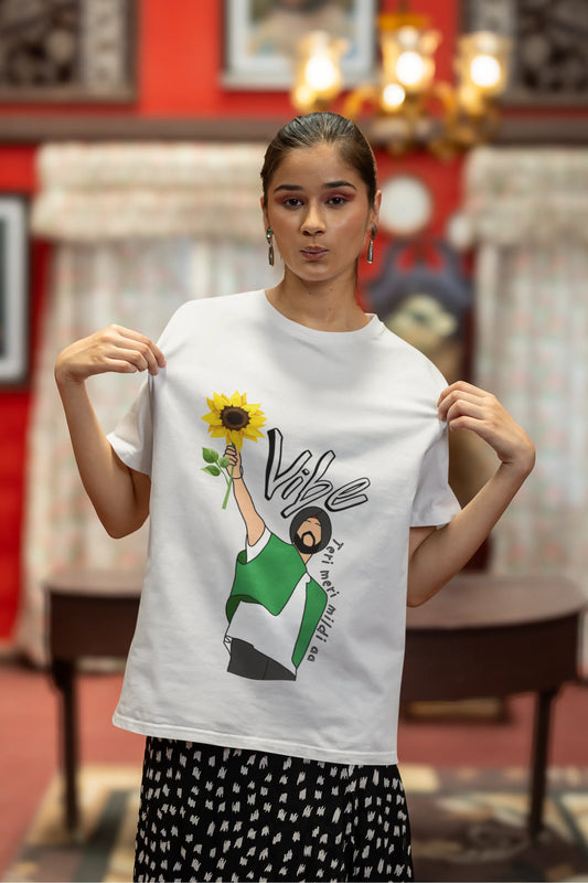 Second front view of female model wearing a off-white oversized t shirt with a design of Diljit Dosanjh holding a sunflower, with the text "Vibe Teri Meri".