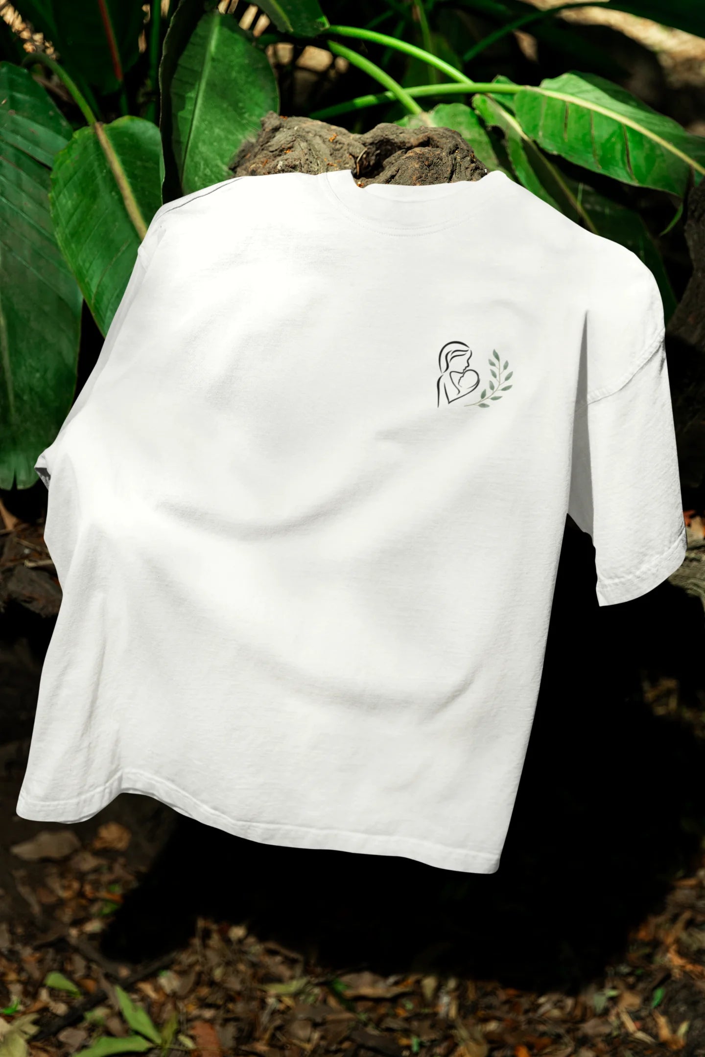 Front view of an off-white oversized t-shirt featuring a design depicting a mother tenderly holding a baby