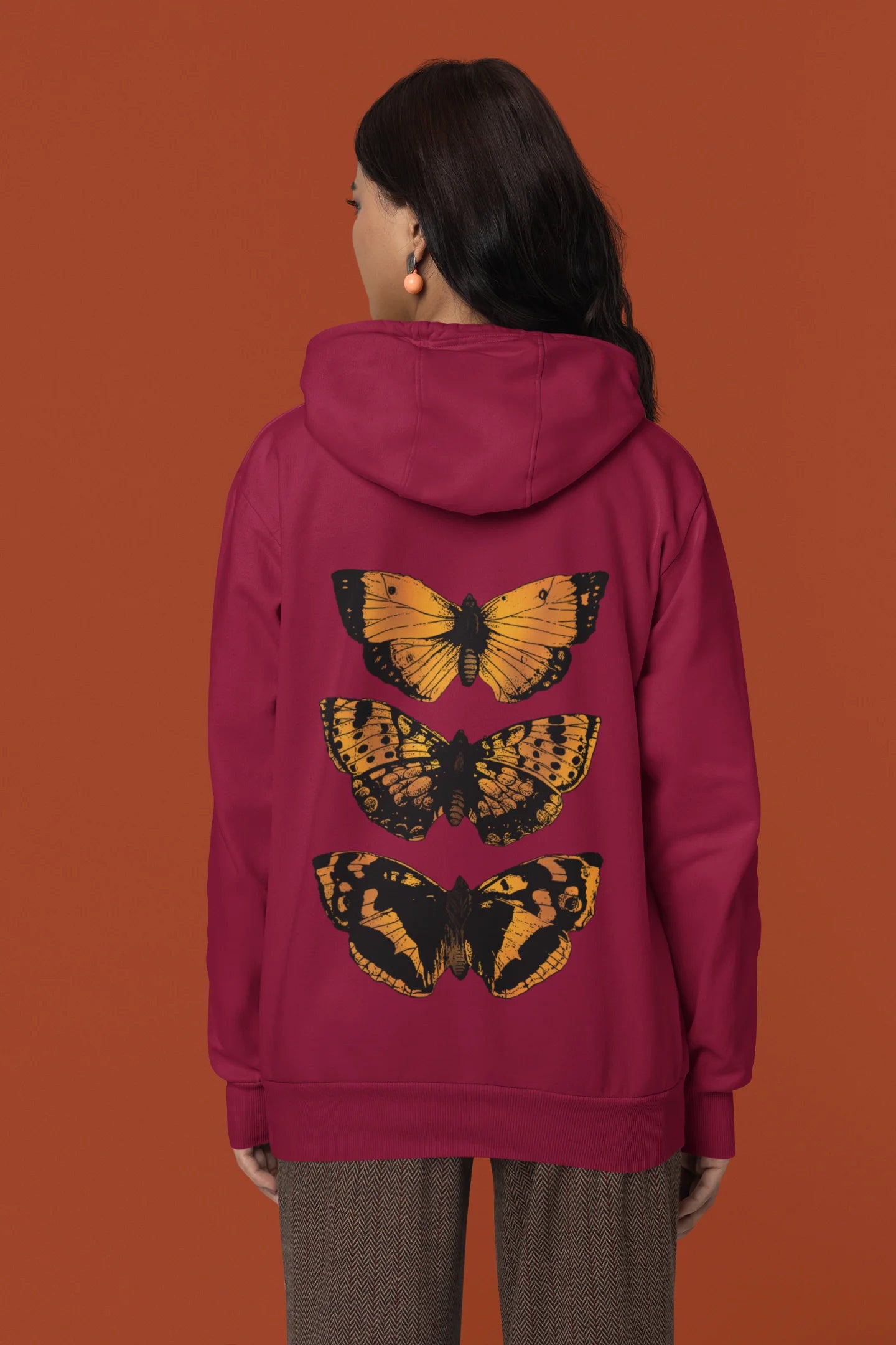 Back view of a female model wearing a maroon hoodie with a design featuring three different types of butterflies, symbolizing the beauty and diversity of nature.