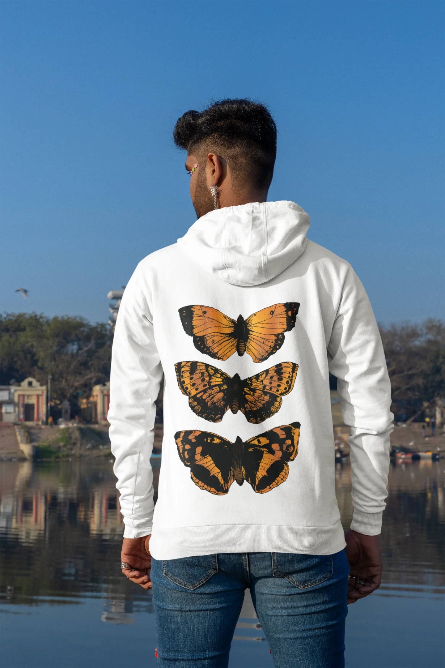 Back view of a male model wearing a white hoodie with a design featuring three different types of butterflies, symbolizing the beauty and diversity of nature.