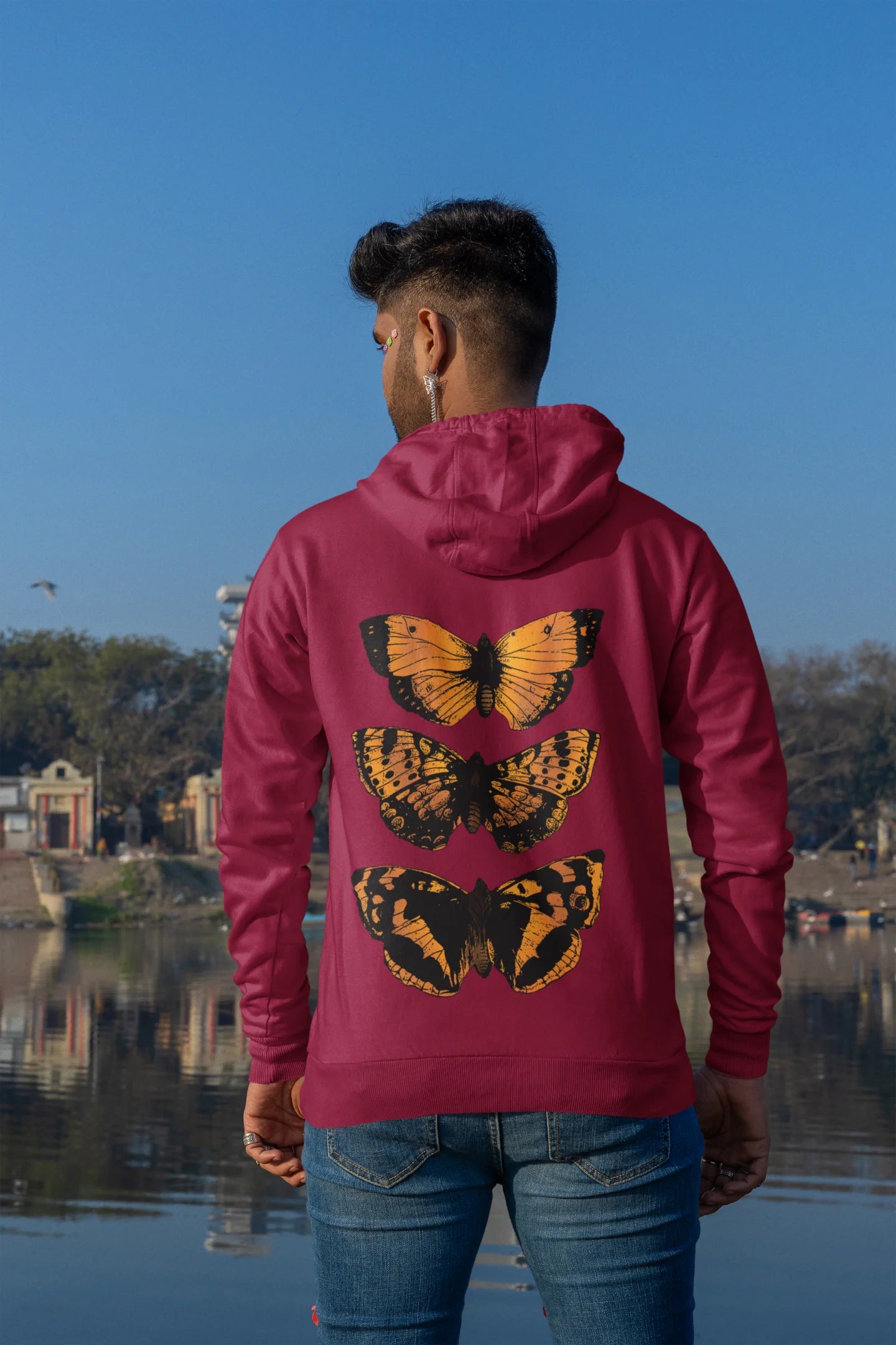 Back view of a male model wearing a maroon hoodie with a design featuring three different types of butterflies, symbolizing the beauty and diversity of nature.