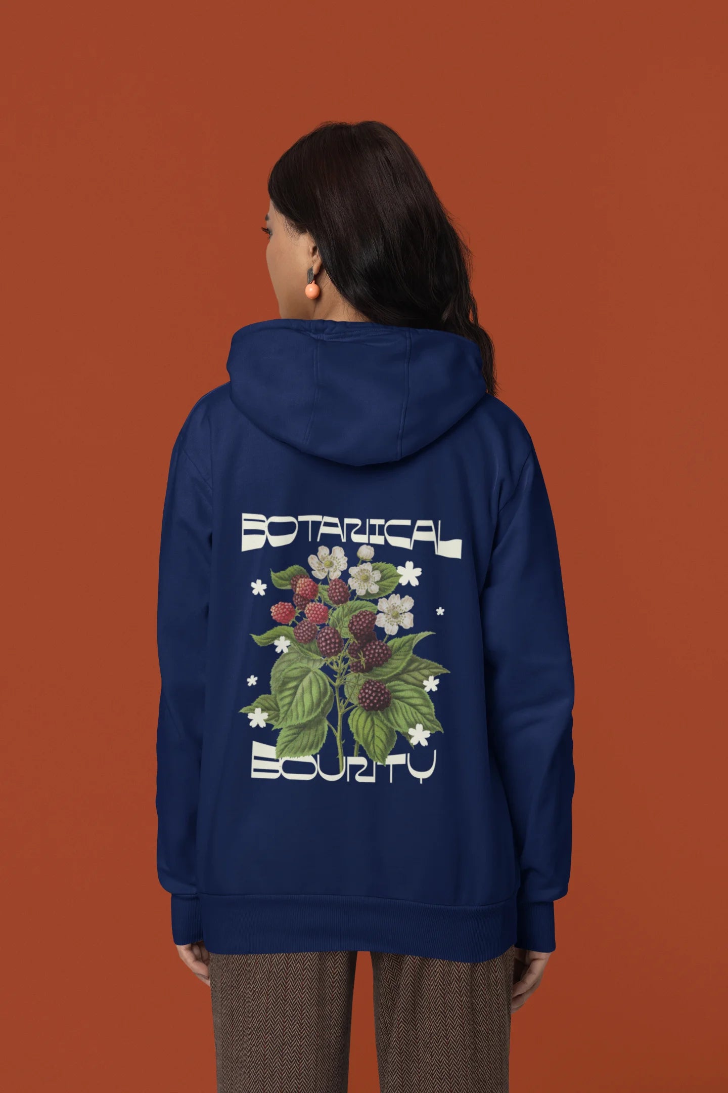 Back view of a female model model wearing a navy hoodie with a design featuring berry bushes overflowing with fruit, symbolizing the abundance and beauty of nature.