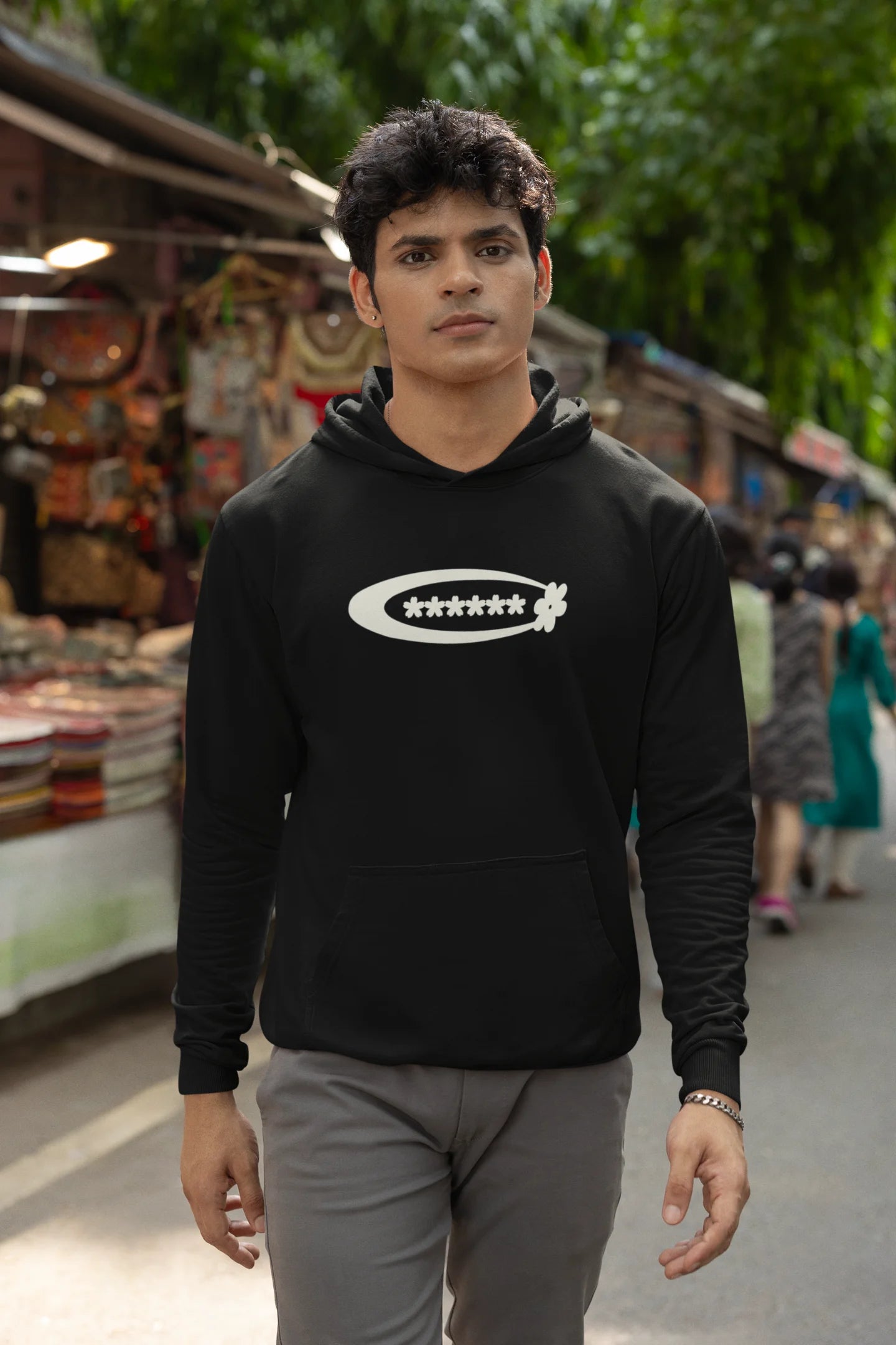 First front view of a male model model wearing a black hoodie with a design featuring berry bushes overflowing with fruit, symbolizing the abundance and beauty of nature.