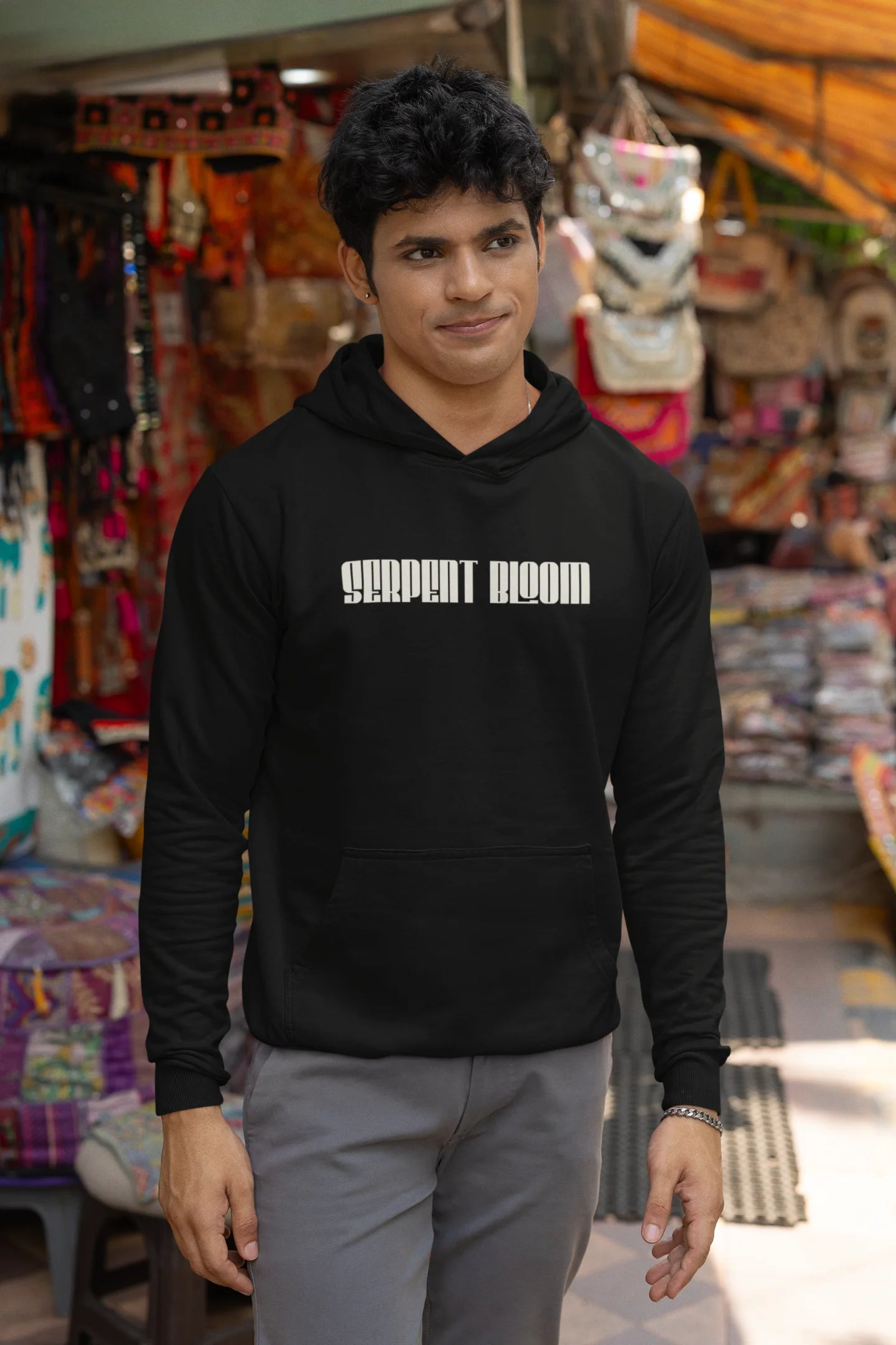 First front of male model wearing a black hoodie with a snake coiled around flowers, symbolizing the harmony between nature and its creatures.
