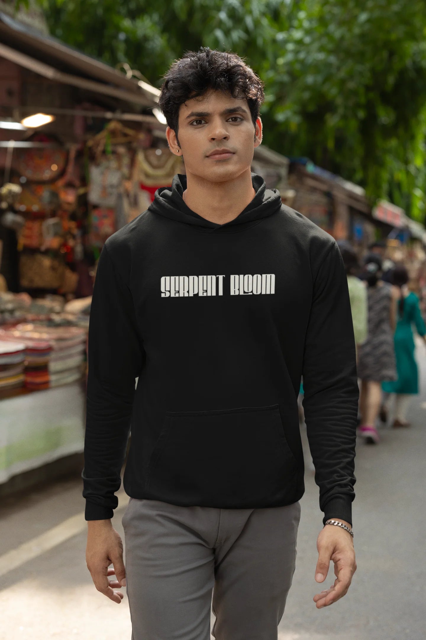 Second front of male model wearing a black hoodie with a snake coiled around flowers, symbolizing the harmony between nature and its creatures.