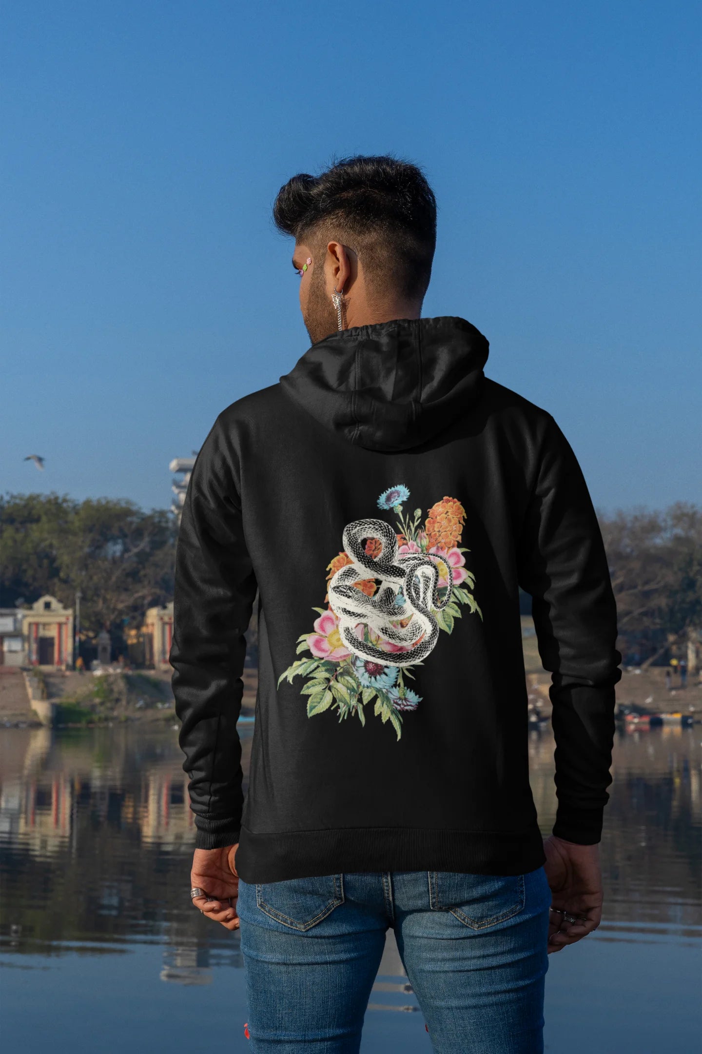 Back view of male model wearing a black hoodie with a snake coiled around flowers, symbolizing the harmony between nature and its creatures.