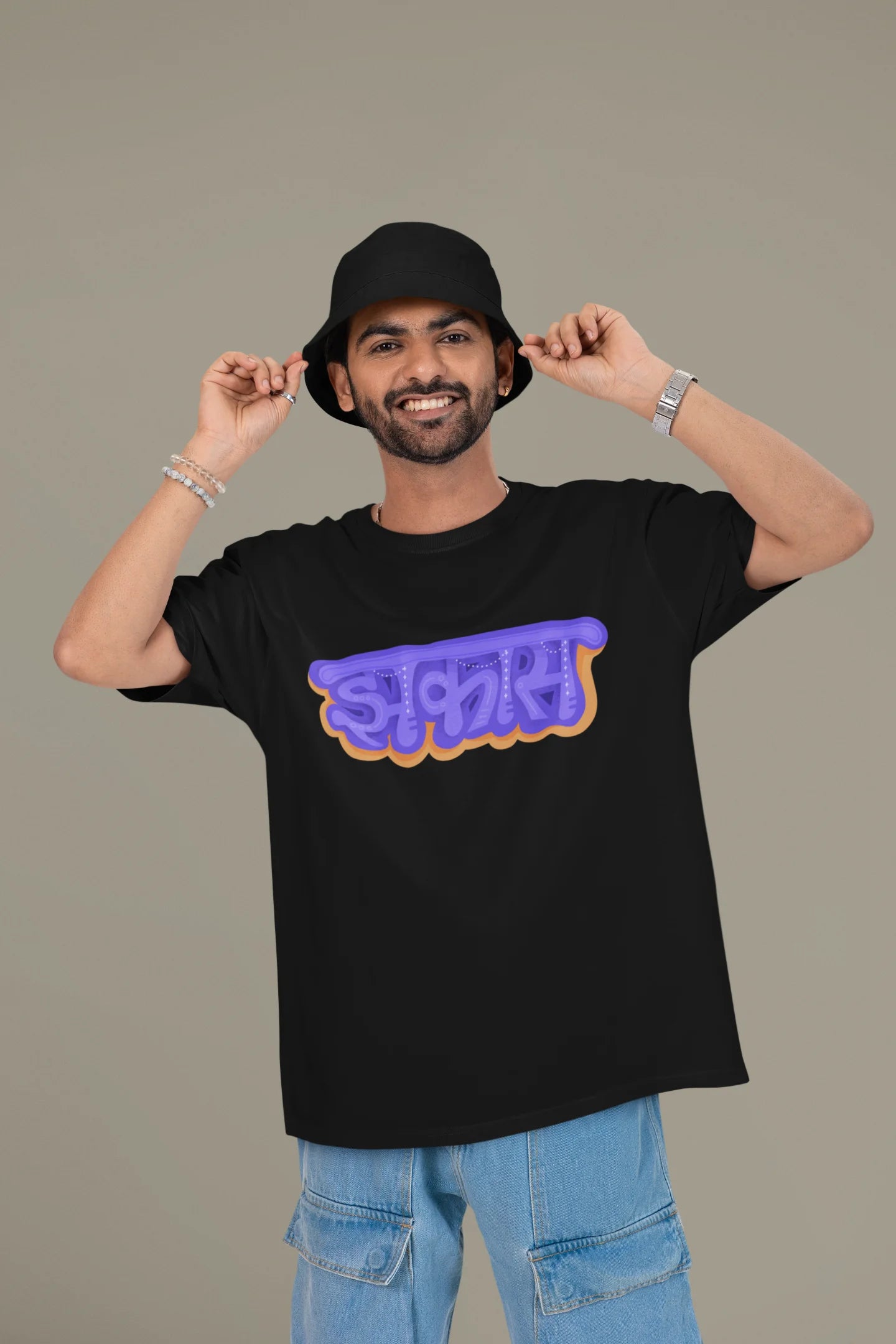 2nd front view of a male model wearing an black oversized t-shirt featuring "Jhakas" in a stylish font.