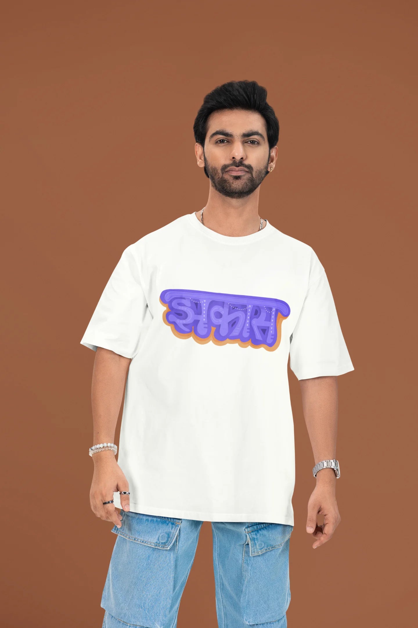 First front view of a male model wearing an off-white oversized t-shirt featuring "Jhakas" in a stylish font.