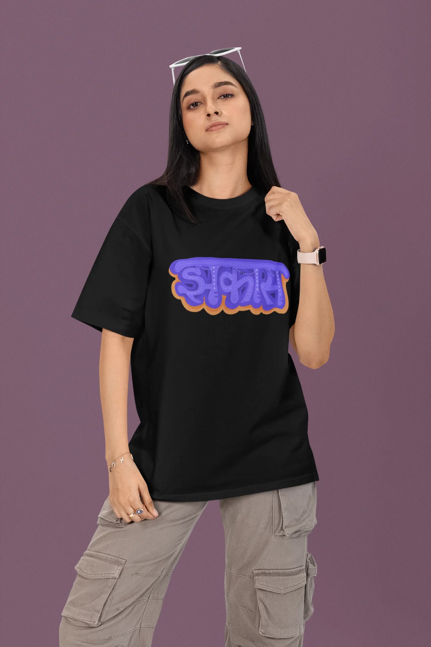 First front view of a female model wearing an black oversized t-shirt featuring "Jhakas" in a stylish font.