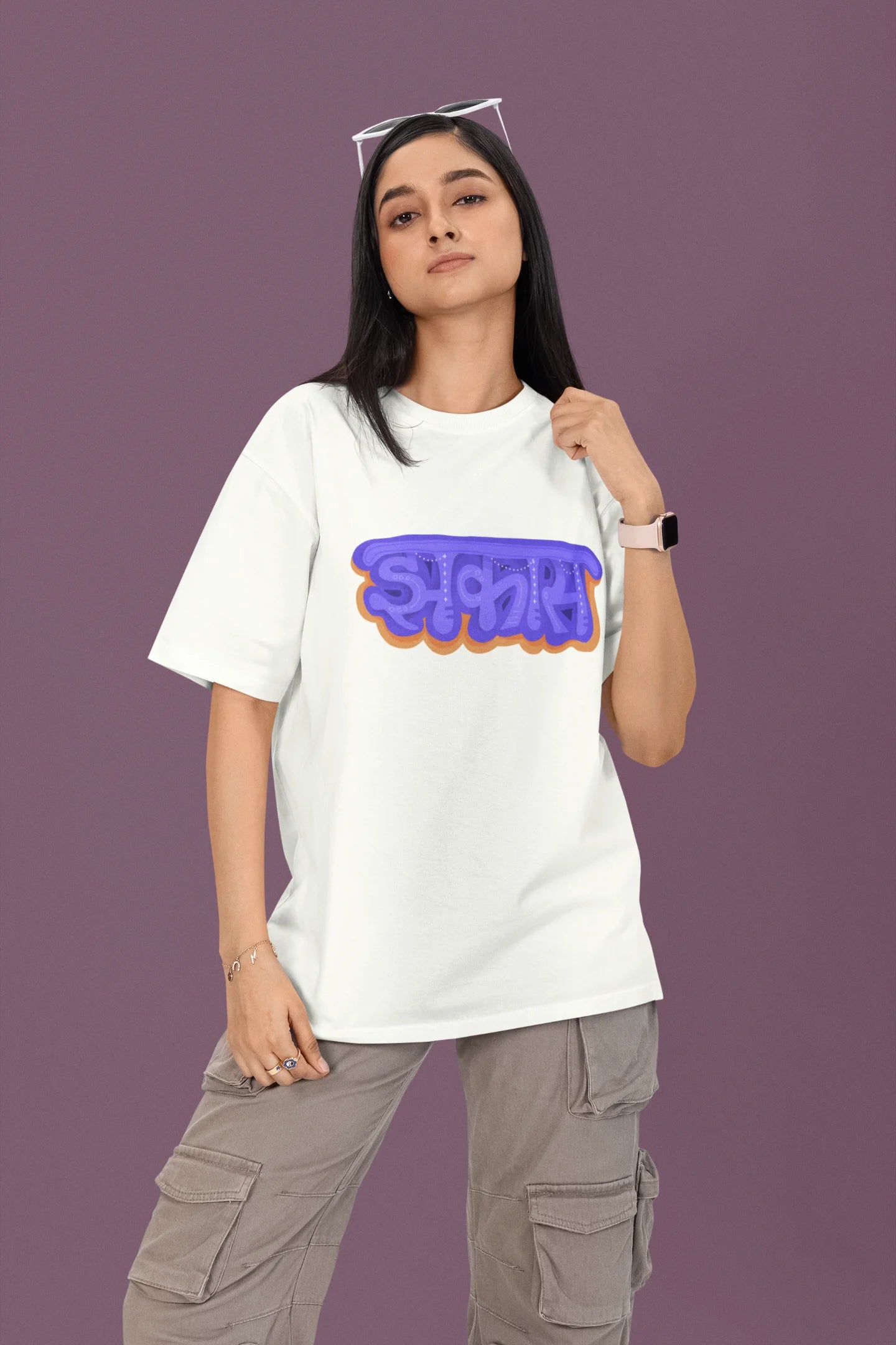 First front view of a female model wearing an off-white oversized t-shirt featuring "Jhakas" in a stylish font.