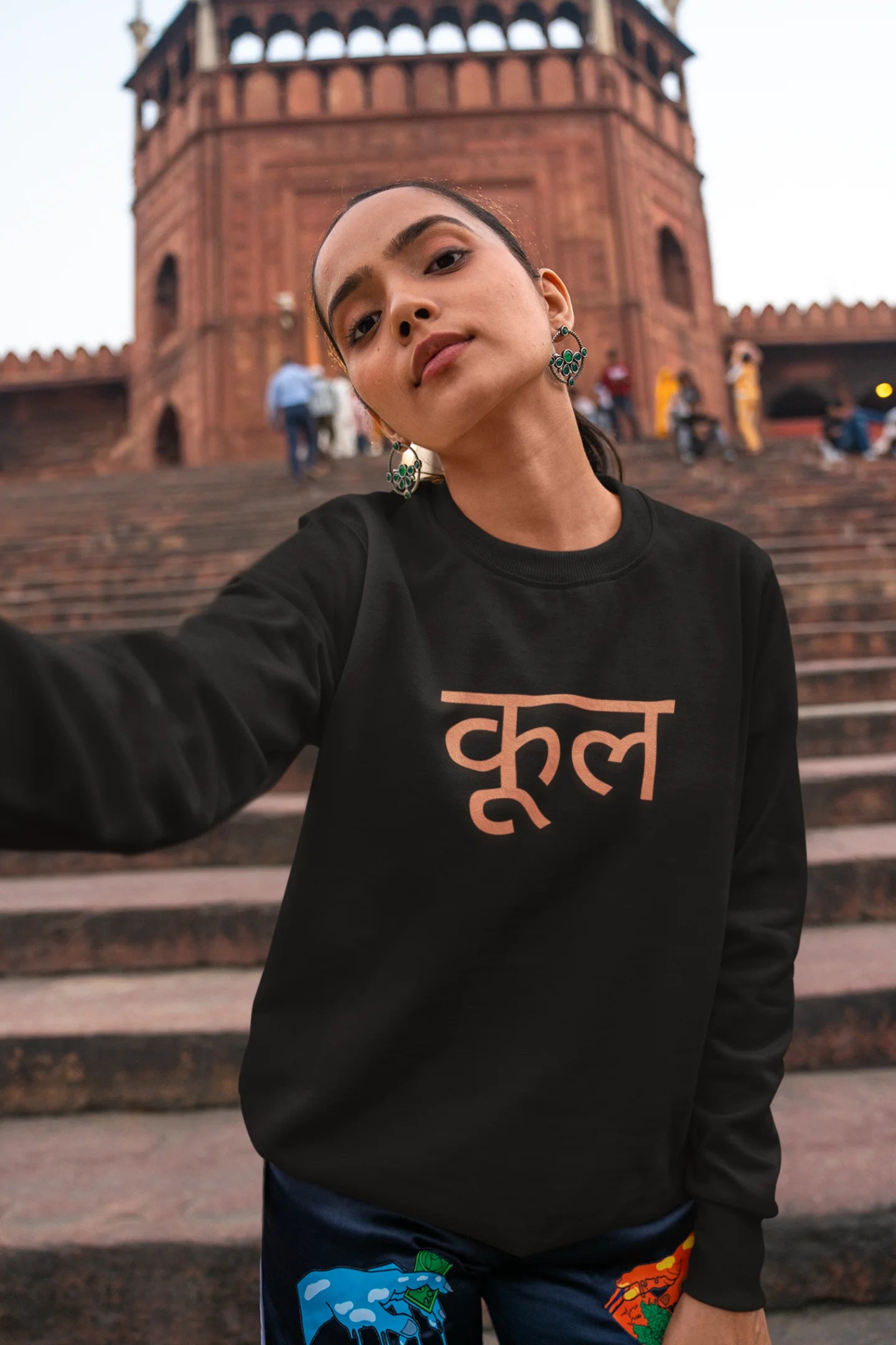 First front view of a female model wearing a black oversized t-shirt featuring the Hindi word for "cool" with a unique, playful design.