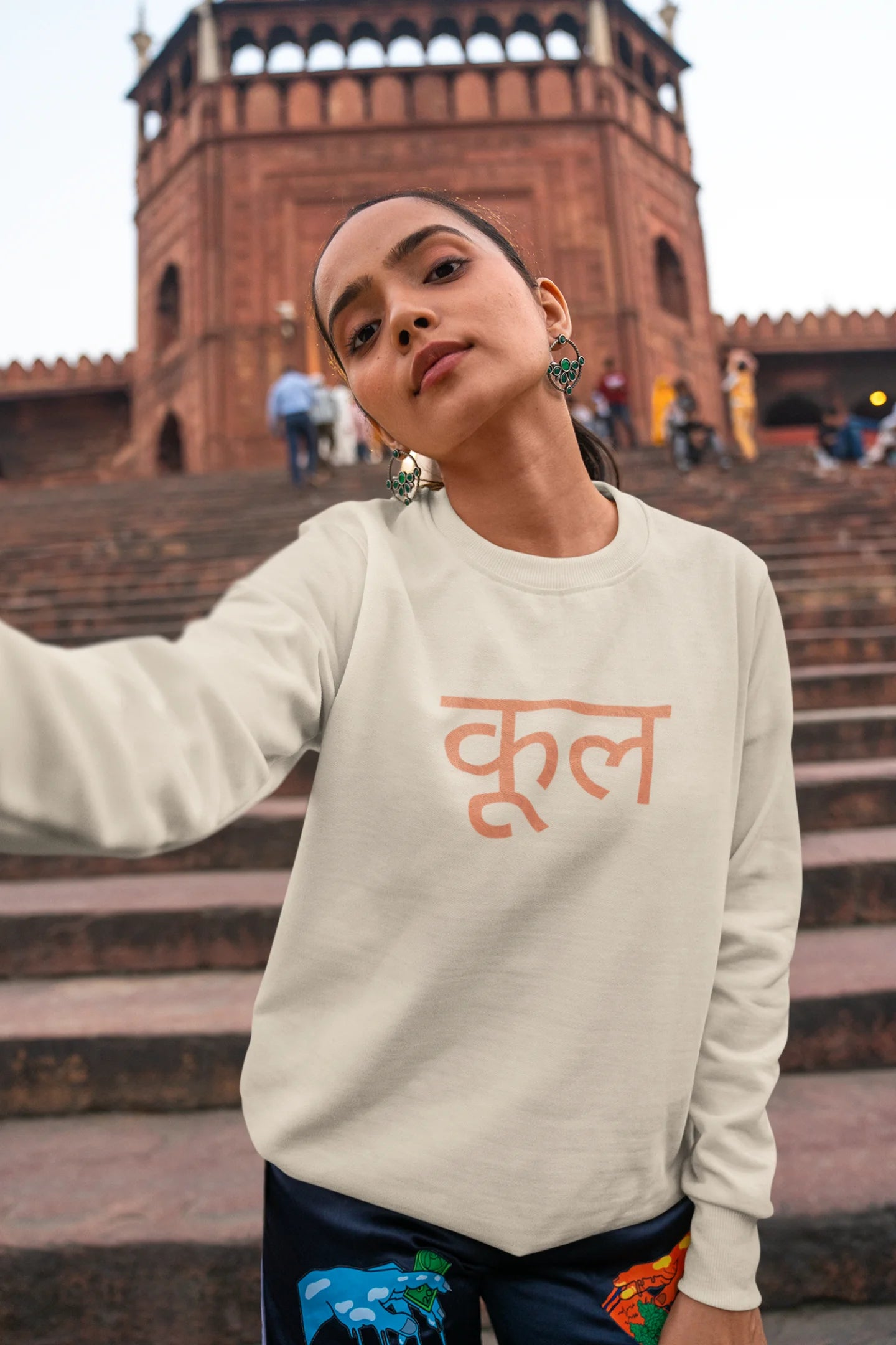 3rd front view of a female model wearing a cream oversized t-shirt featuring the Hindi word for "cool" with a unique, playful design.