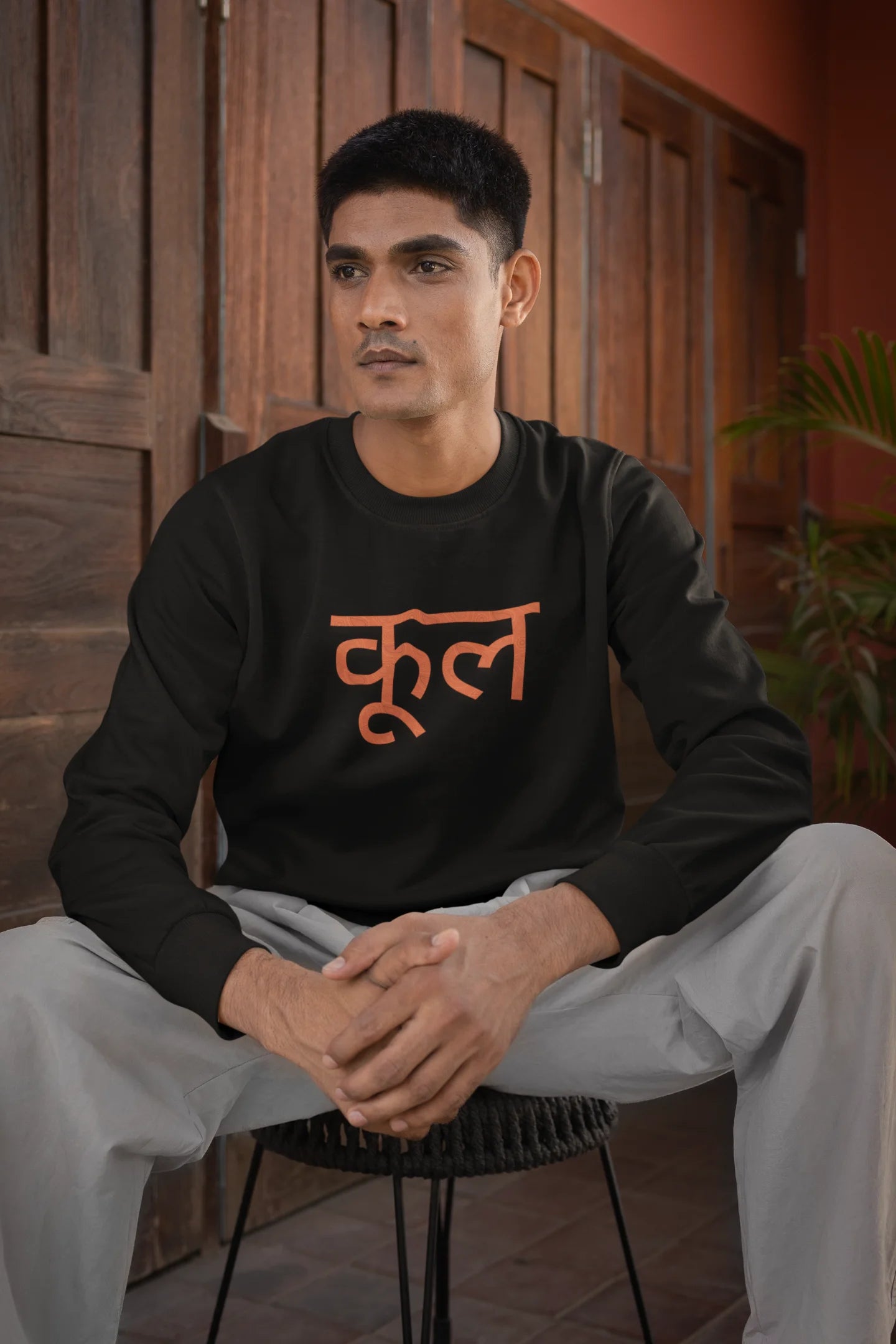 First front view of a male model wearing a black oversized t-shirt featuring the Hindi word for "cool" with a unique, playful design.