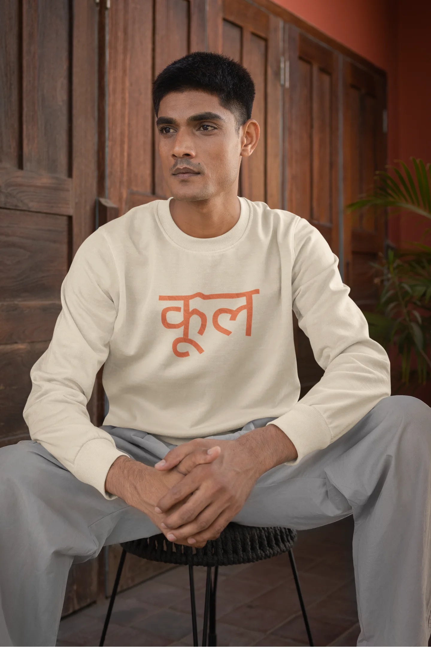First front view of a male model wearing a cream oversized t-shirt featuring the Hindi word for "cool" with a unique, playful design.