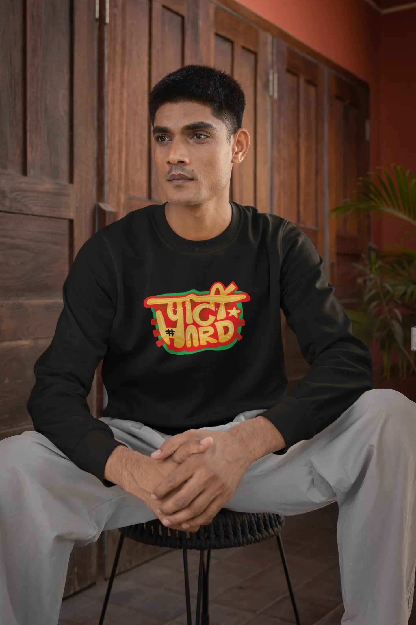 First front view of a male model wearing a black oversized t-shirt with the phrase "Party Hard" in an energetic Hindi.