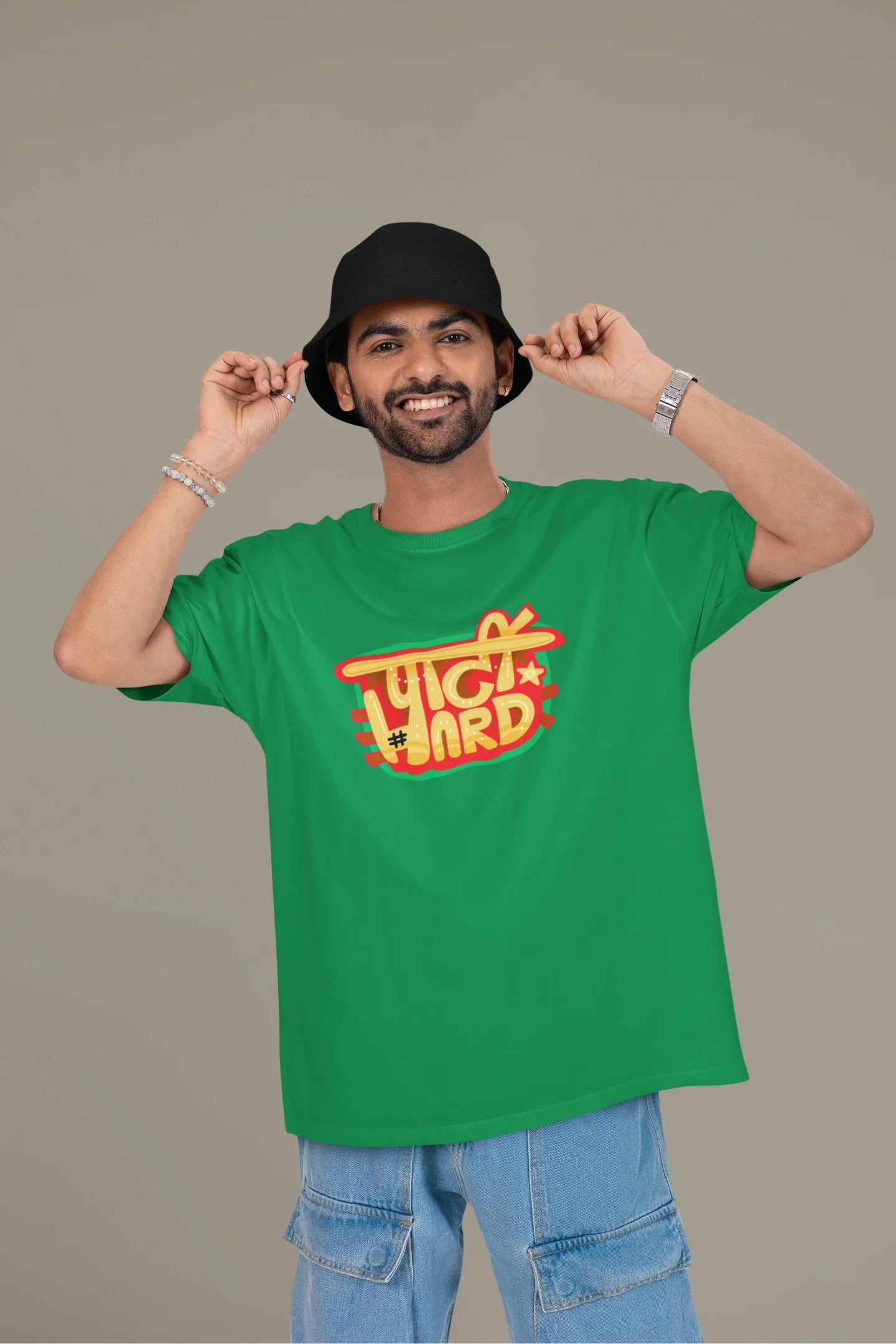 First front view of a male model wearing a forest green oversized t-shirt with the phrase "Party Hard" in an energetic Hindi.