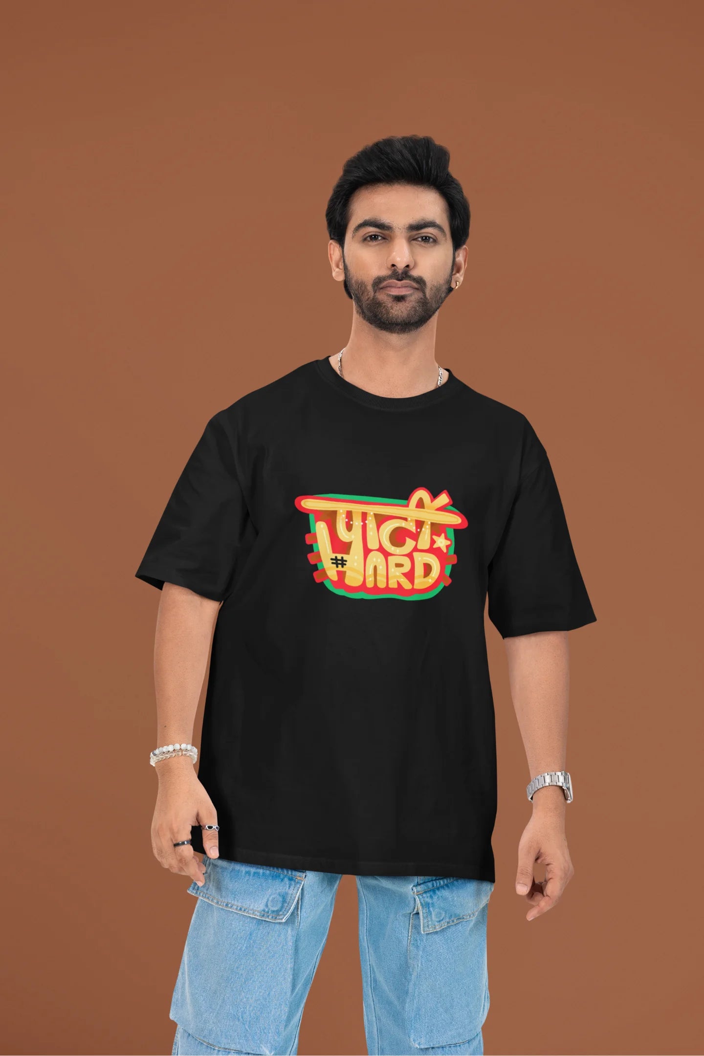 First front view of a male model wearing a black oversized t-shirt with the phrase "Party Hard" in an energetic Hindi.