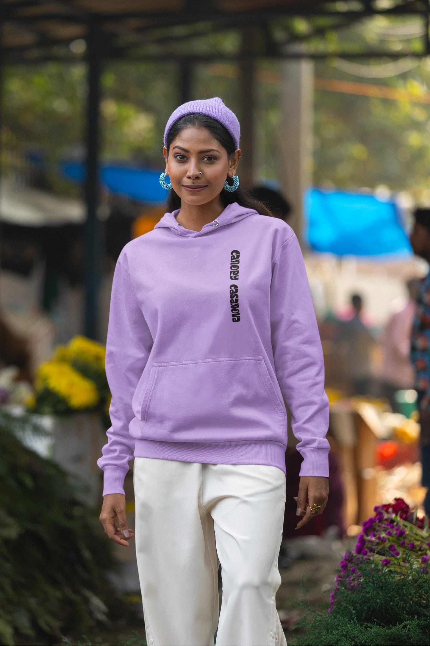 Fourth front view of a female model wearing a lavender hoodie with a toucan perched on a branch in a jungle setting.