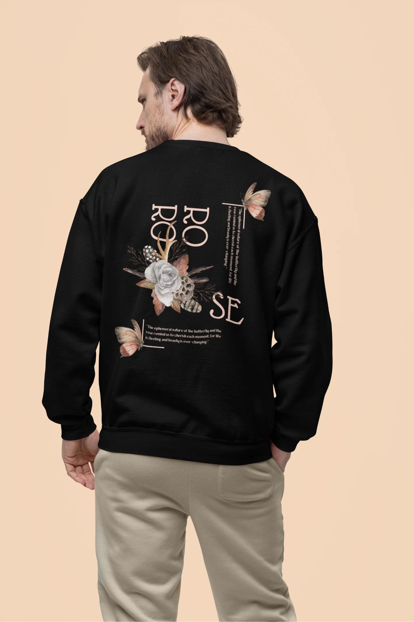 Back view of a male model wearing a black sweatshirt featuring a beautiful rose design with inspirational text, offering a calming and uplifting aesthetic.