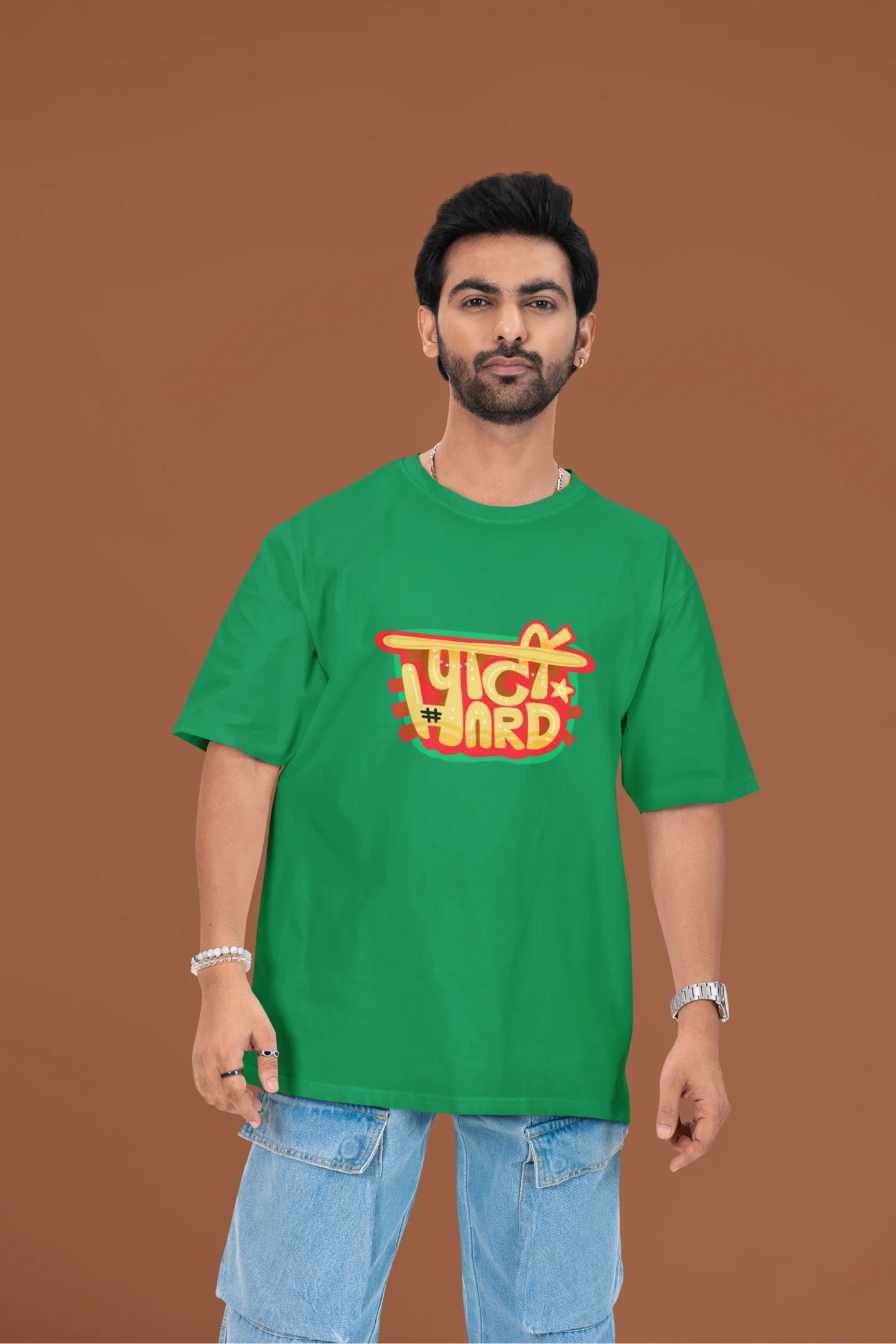 2nd front view of a male model wearing a forest green oversized t-shirt with the phrase "Party Hard" in an energetic Hindi.