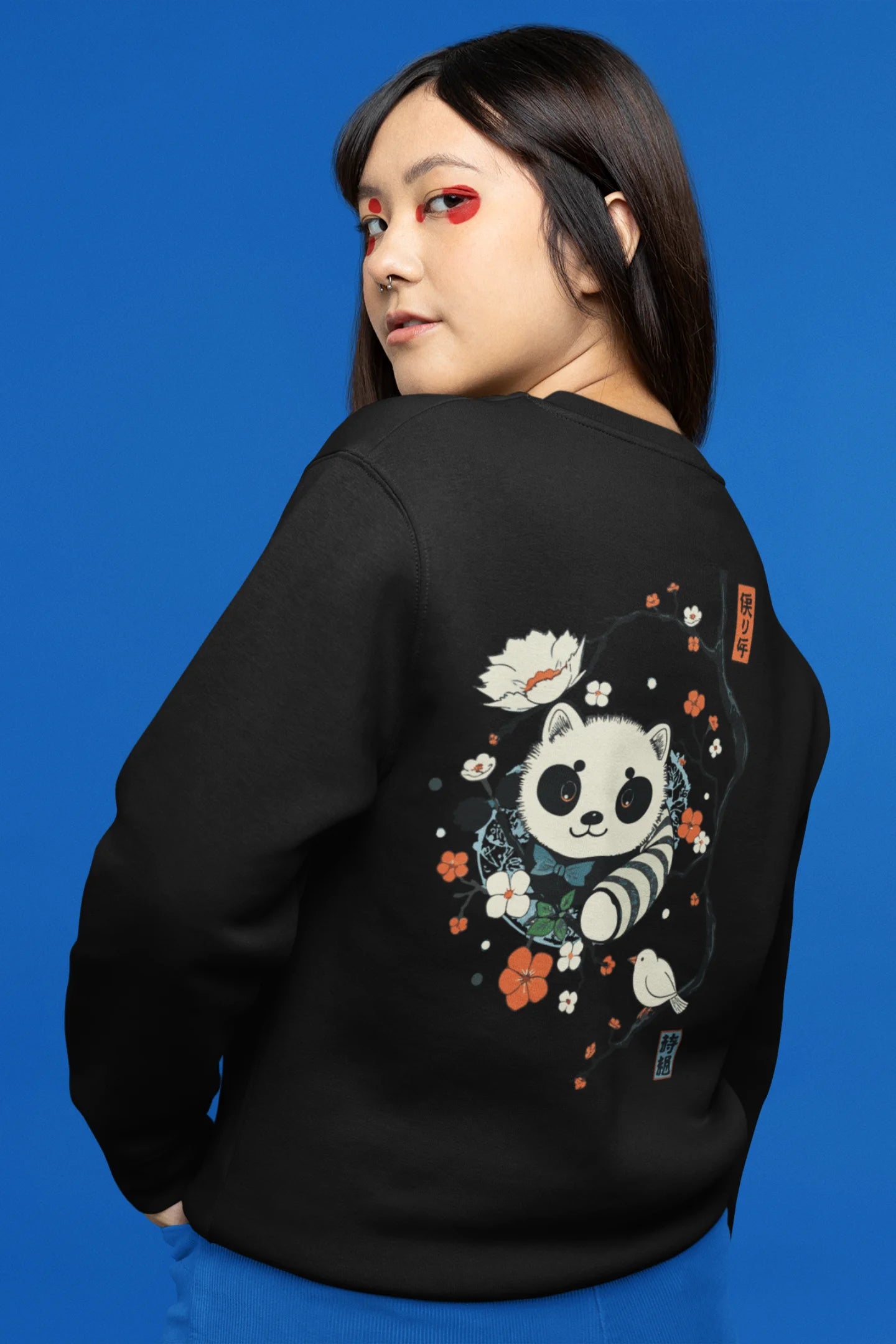 Back view of a female model wearing a black sweatshirt with a panda fox surrounded by bamboo.