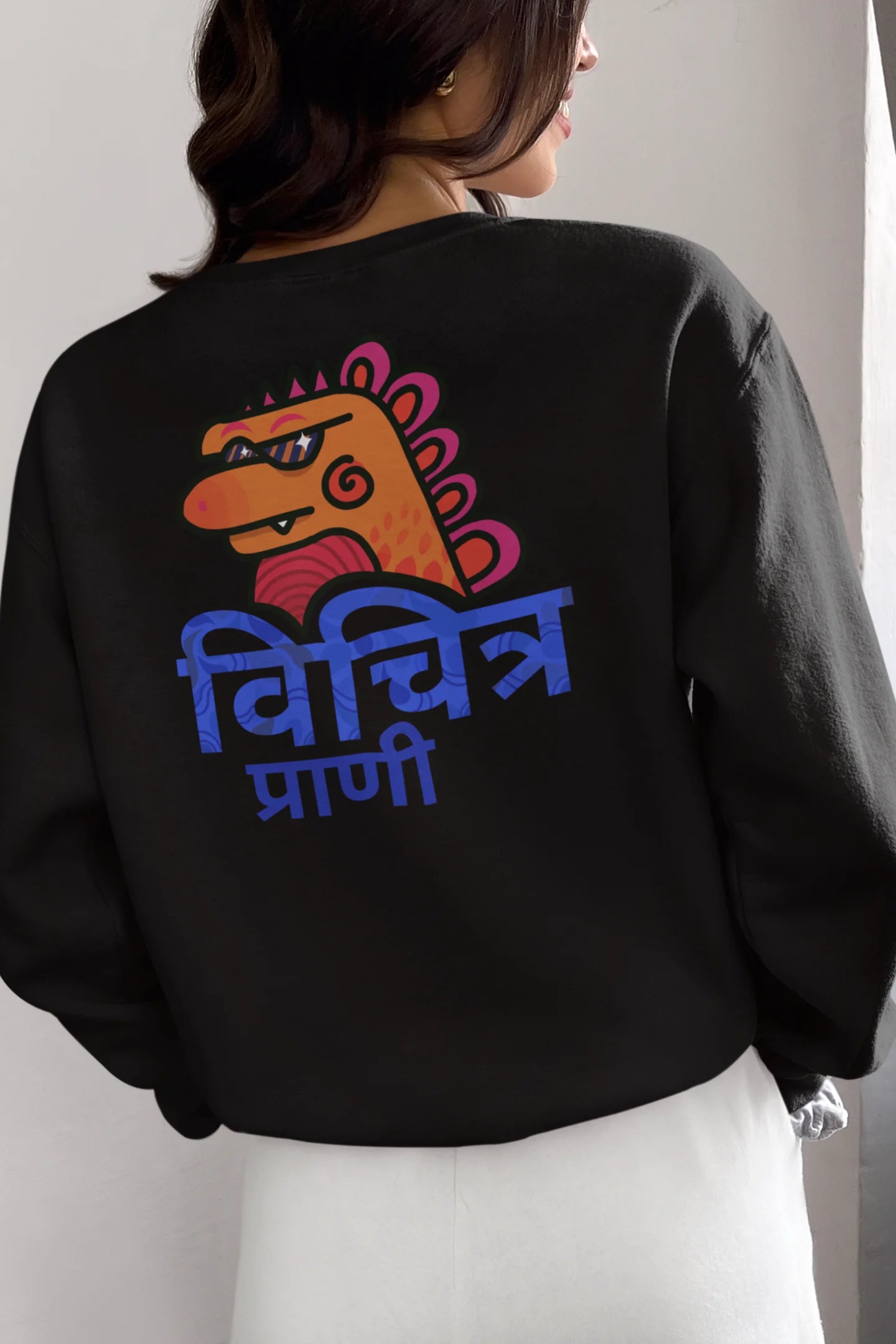 Back view of a female model wearing a black sweatshirt with the phrase "Vichitra Pranee" (meaning "Strange being" or "alien") in a stylish Hindi font.