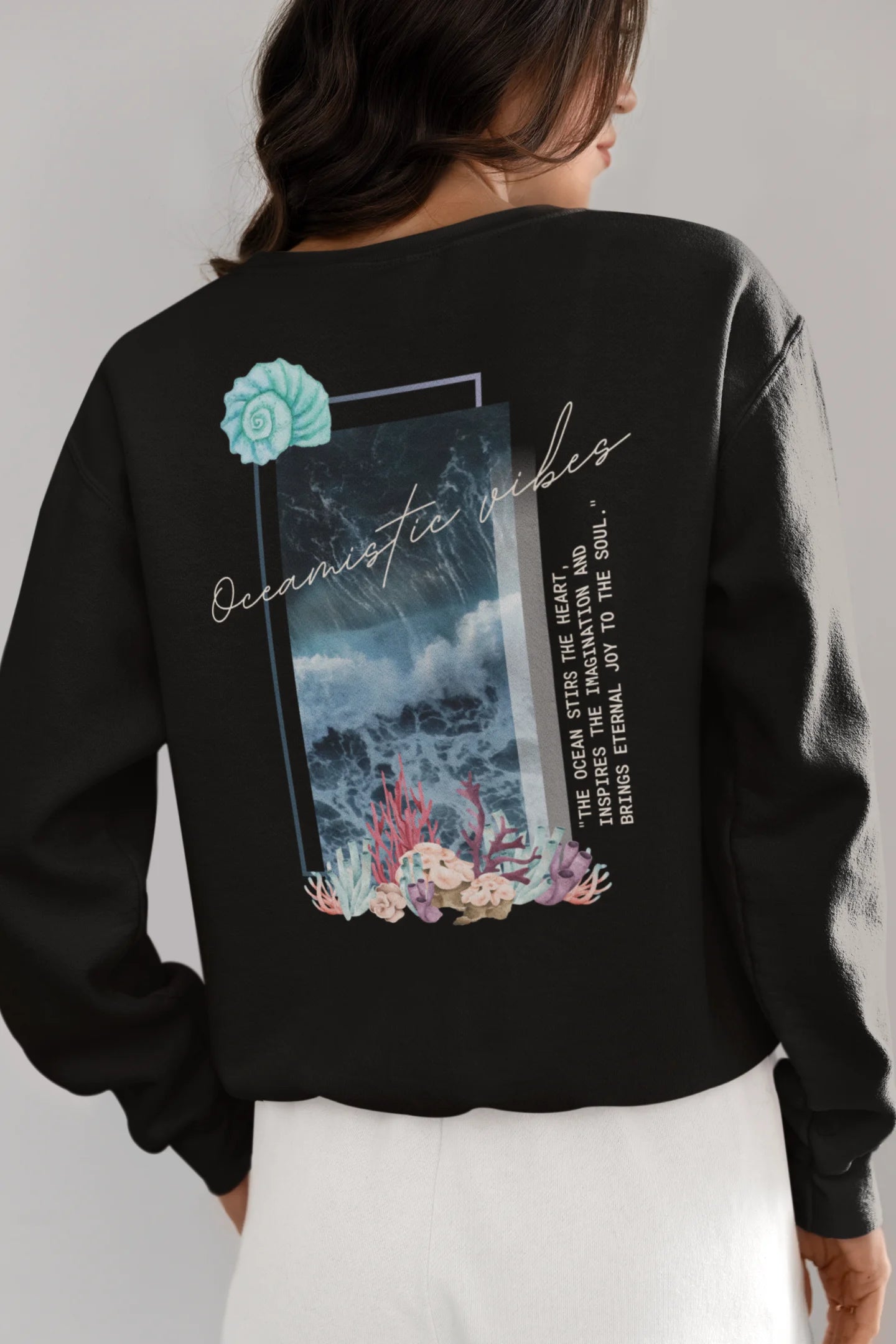 Back view of a female model wearing a black sweatshirt featuring a stunning design of corals and shells, evoking a serene underwater atmosphere.