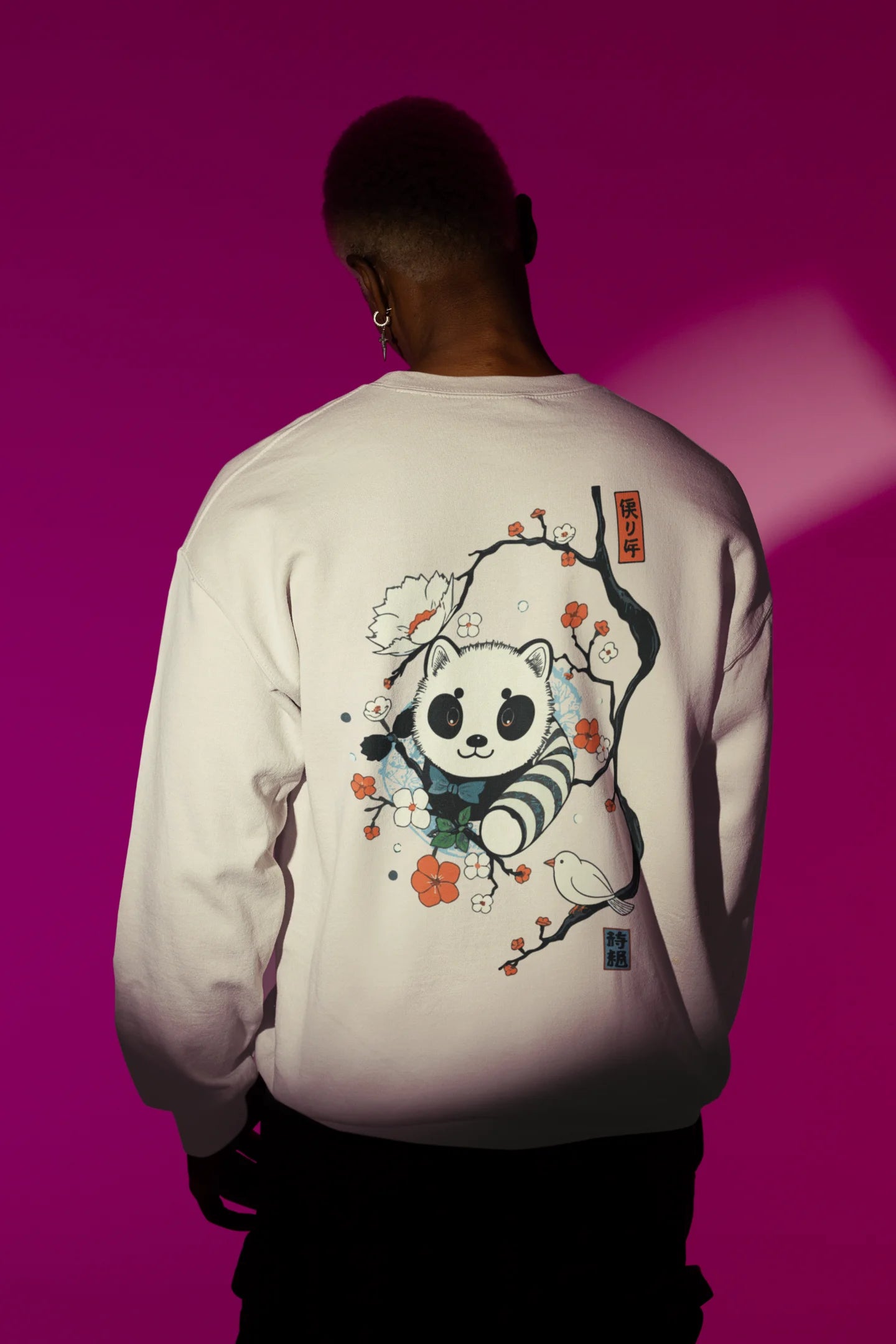 Back view of a male model wearing a cream sweatshirt with a panda fox surrounded by bamboo.