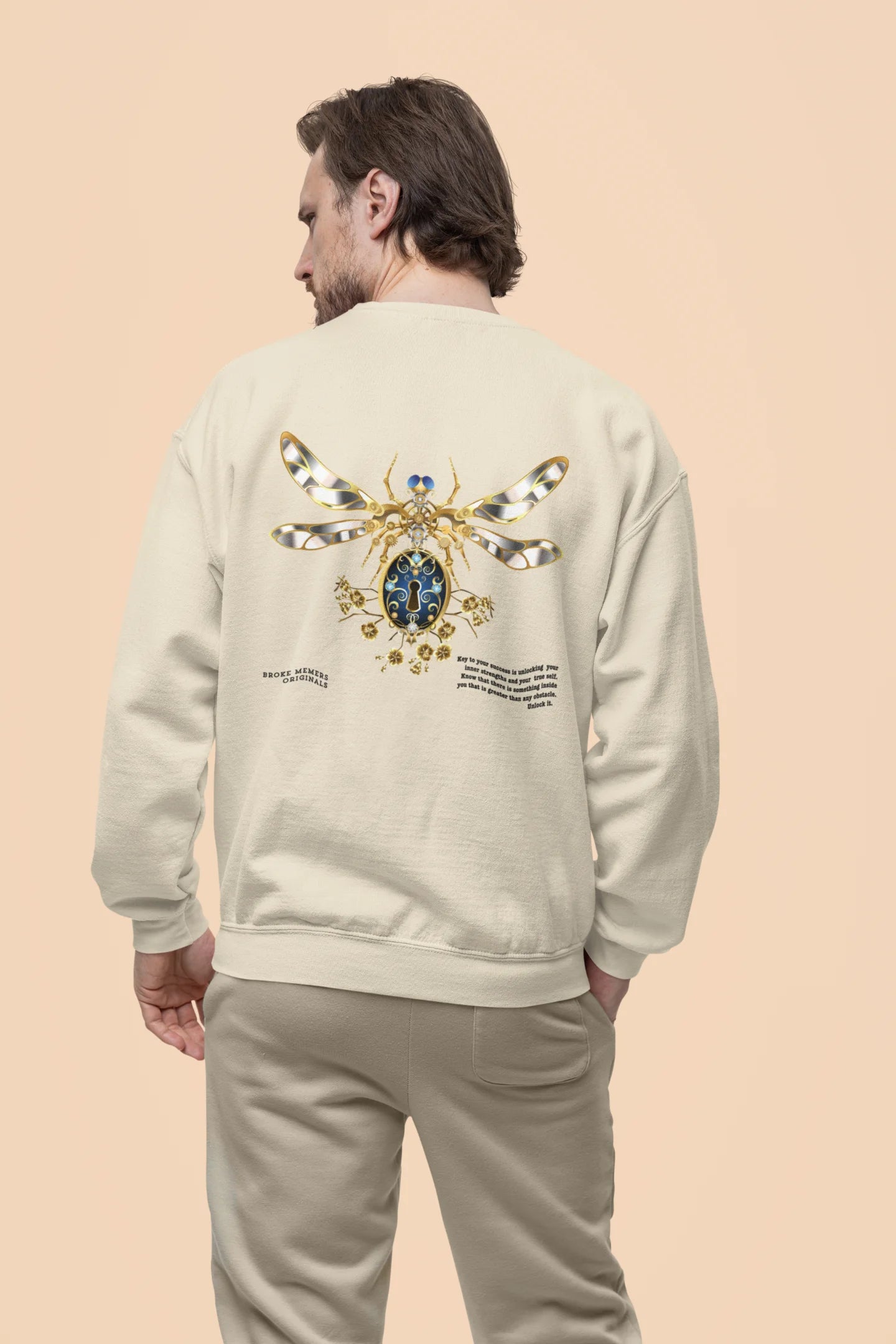 Back view of male model wearing an cream sweatshirt featuring a thought-provoking design of a golden lock shaped like an insect. Ideal for those who love symbolic clothing and unique conversation starters.