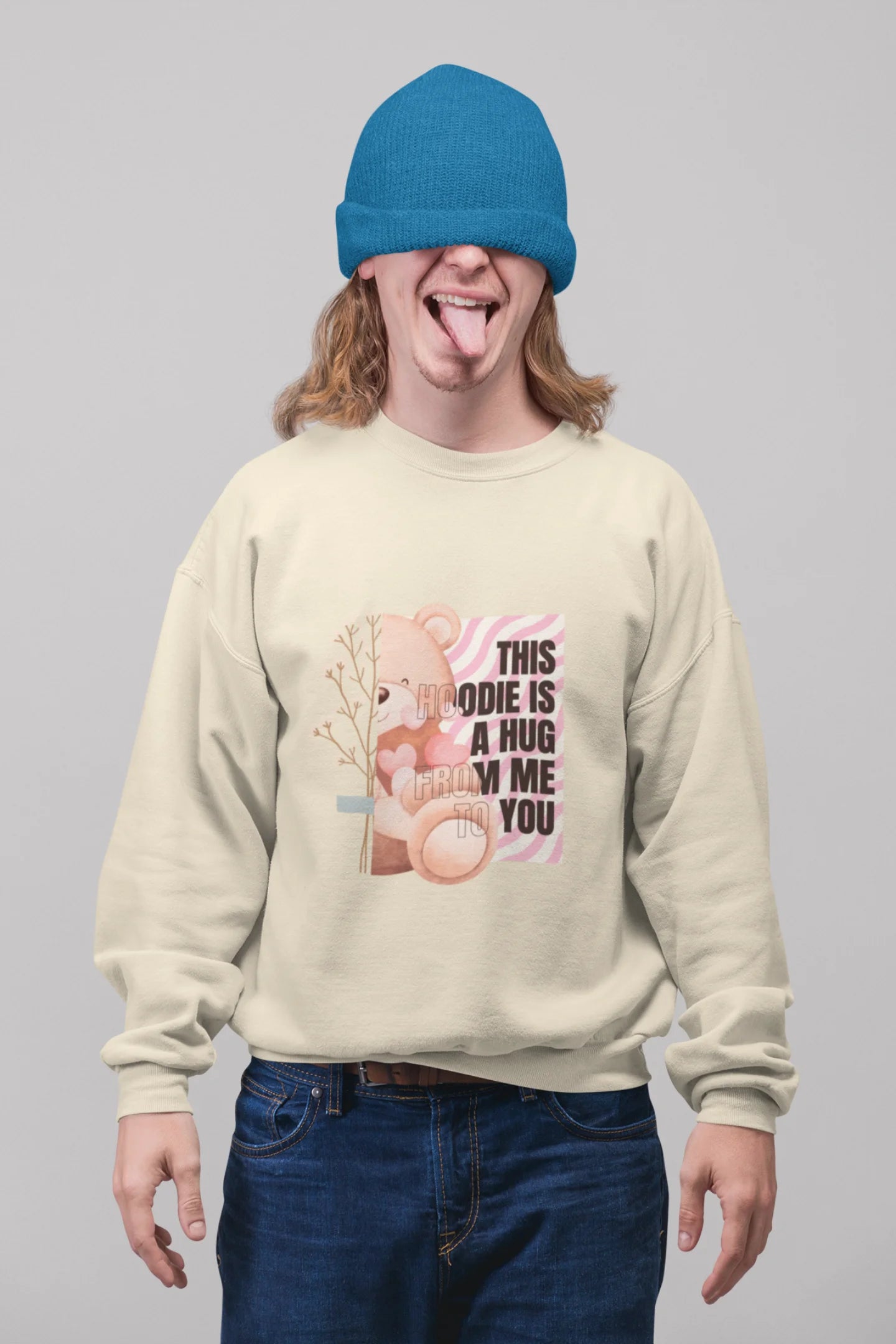 First front view of a male model wearing a cream sweatshirt with a heartwarming design of a teddy bear offering a hug, offering a comforting and relaxing aesthetic.