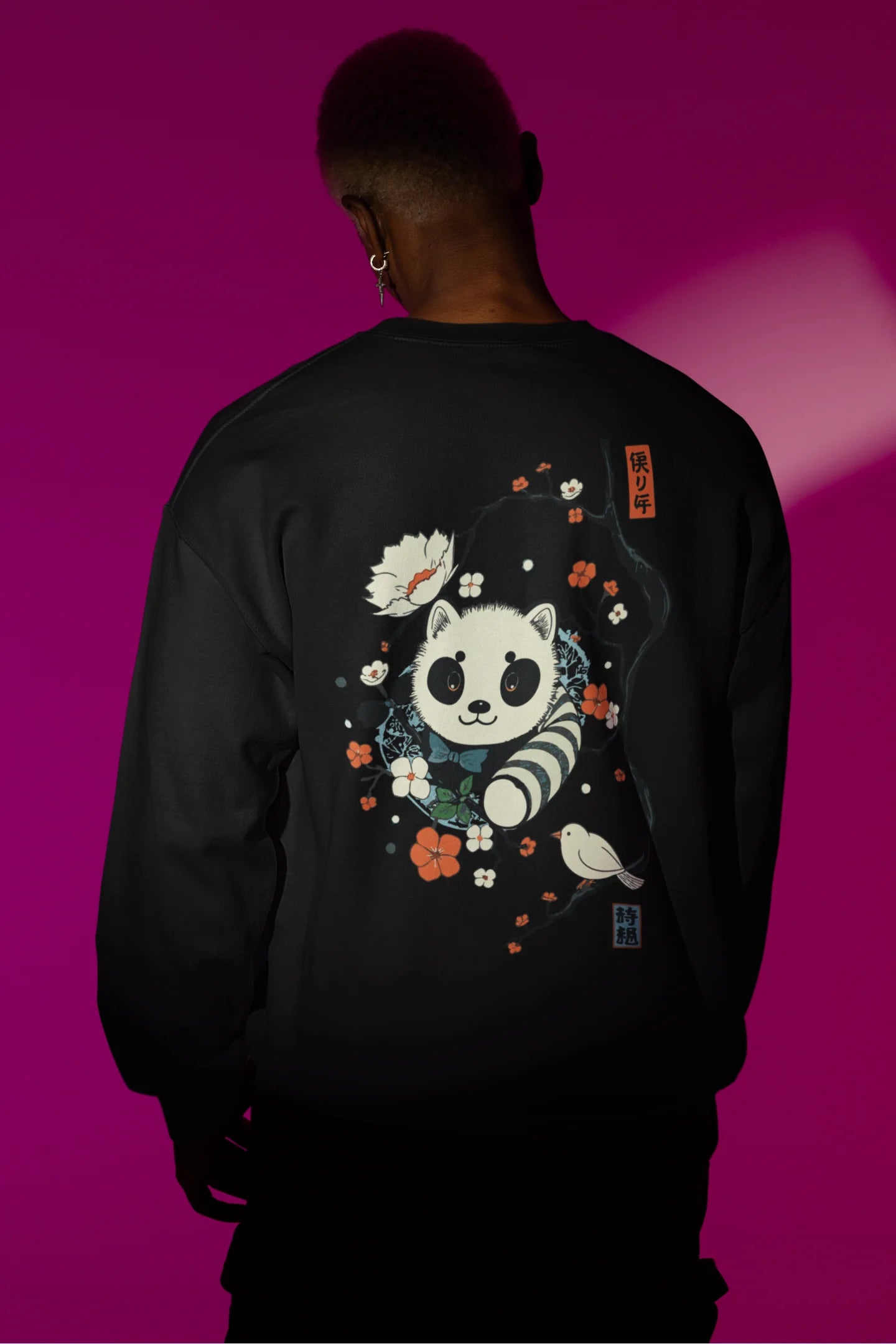 Back view of a male model wearing a black sweatshirt with a panda fox surrounded by bamboo.