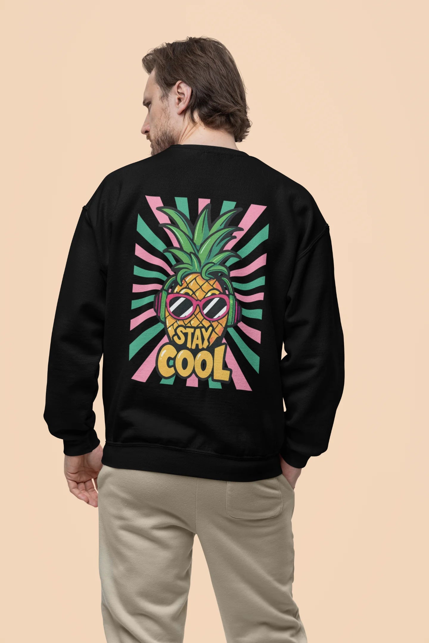 Back view of a male model wearing a trendy black sweatshirt featuring a pineapple wearing sunglasses with the slogan Stay Cool.