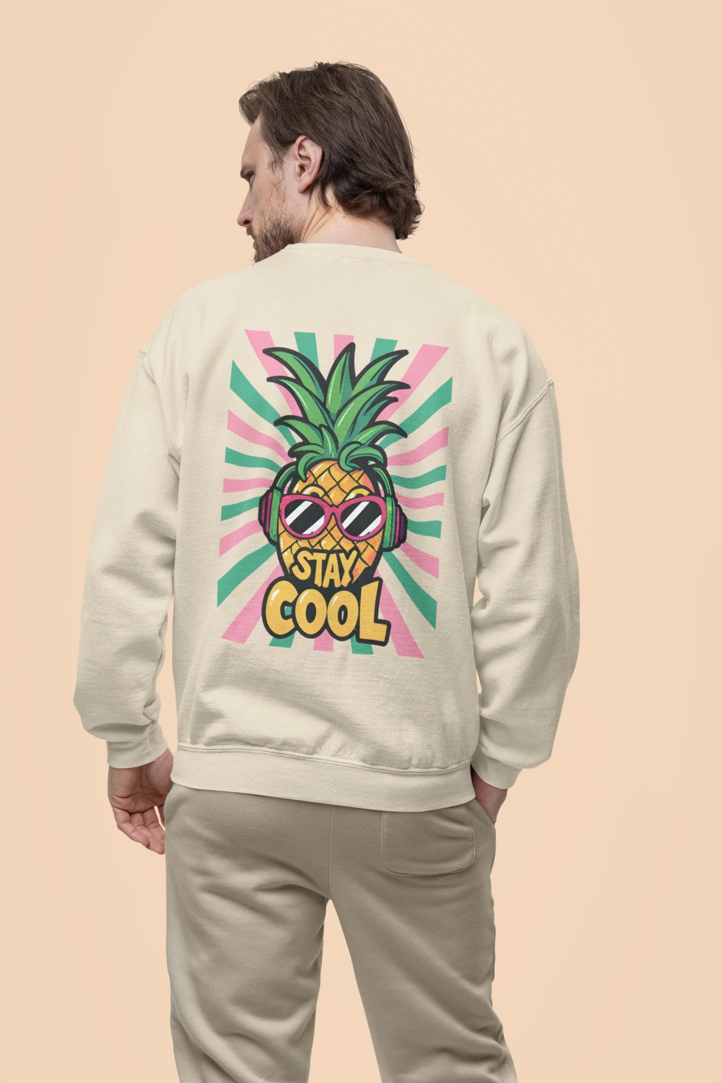 Back view of a male model wearing a trendy cream sweatshirt featuring a pineapple wearing sunglasses with the slogan Stay Cool.