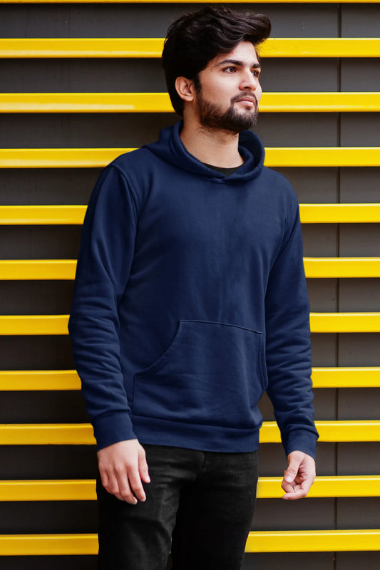 First front view of a male model wearing a navy blue hoodie with a design of a wildcat sitting on ocean waves.