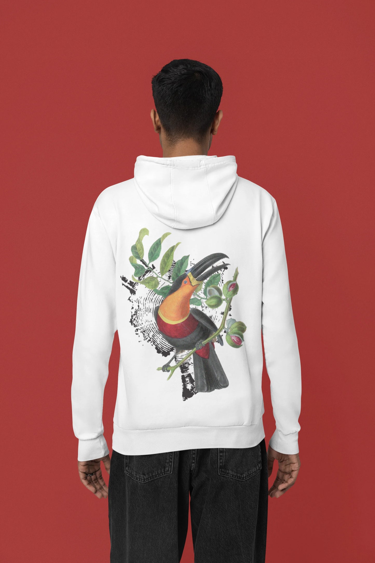 Back view of a male model wearing a white hoodie with a toucan perched on a branch in a jungle setting.