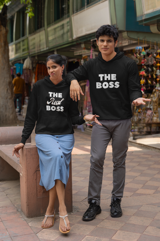 A couple wearing matching hoodies, one with "The Boss" and the other with "The Real Boss" printed on them.