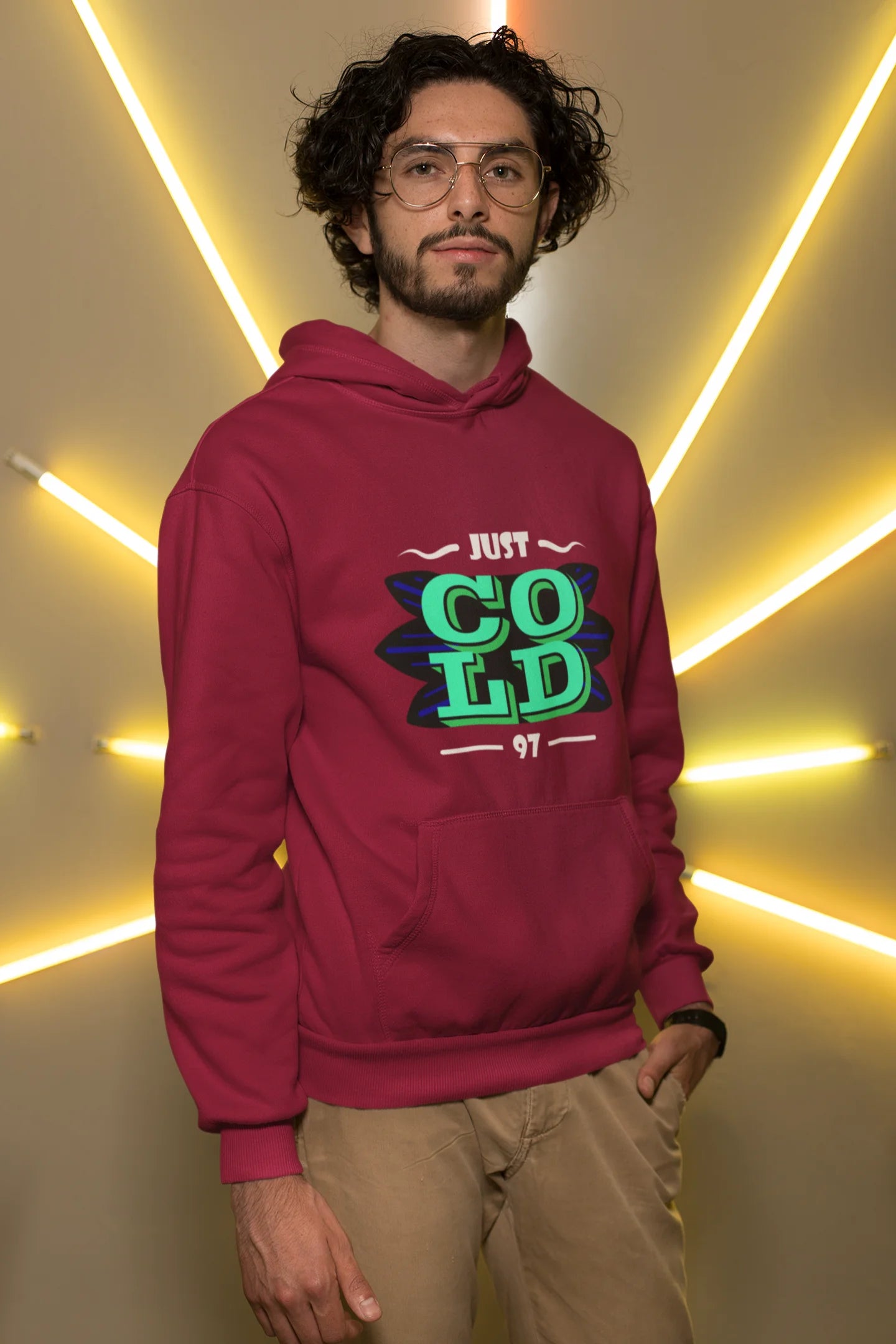 3rd front view of a male model wearing an maroon sweatshirt with the text "Just Cold" printed on it.