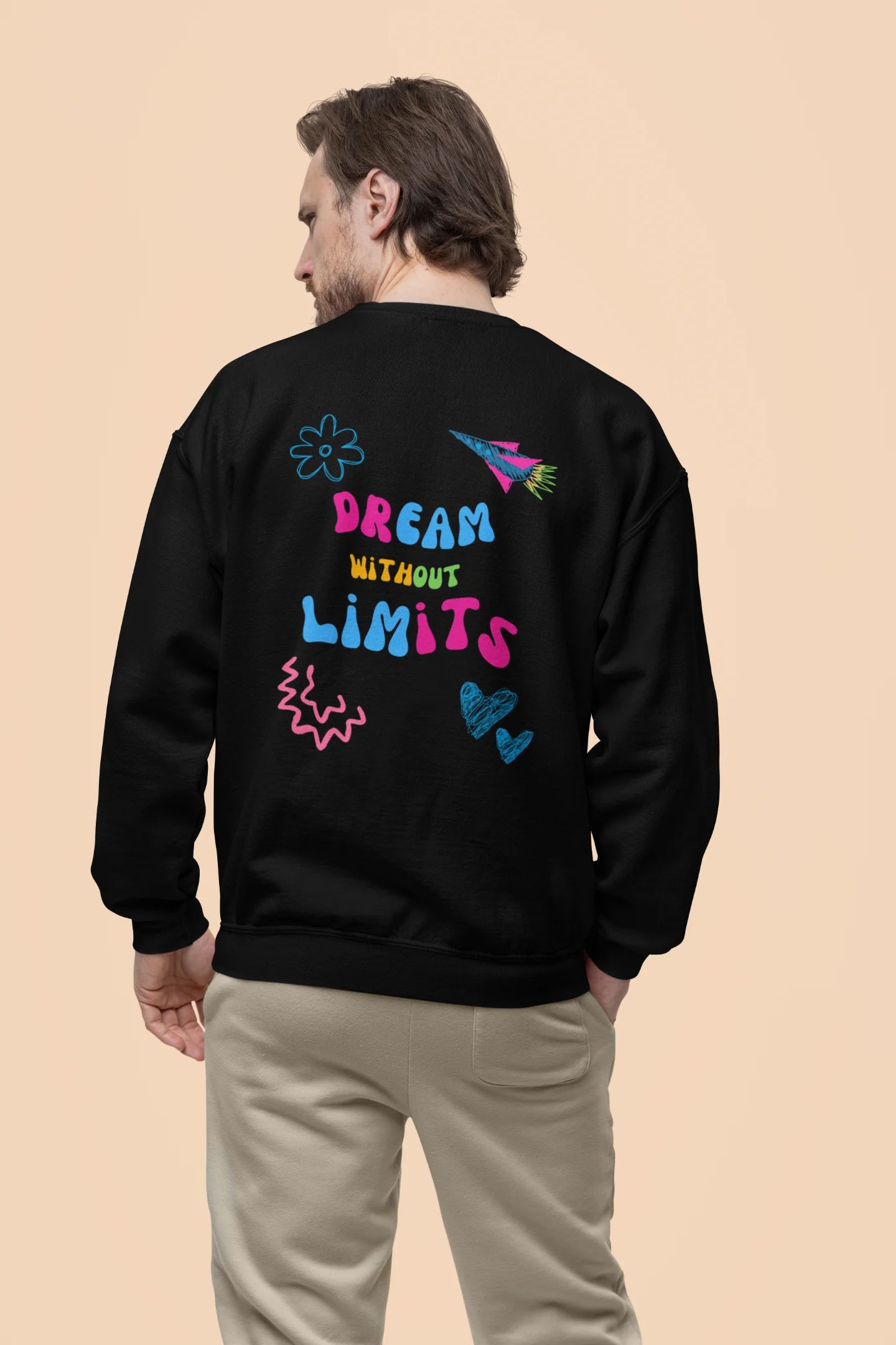 Back view of a male model wearing an black sweatshirt featuring colorful "Dream Without Limits" text, offering an inspiring and uplifting aesthetic.