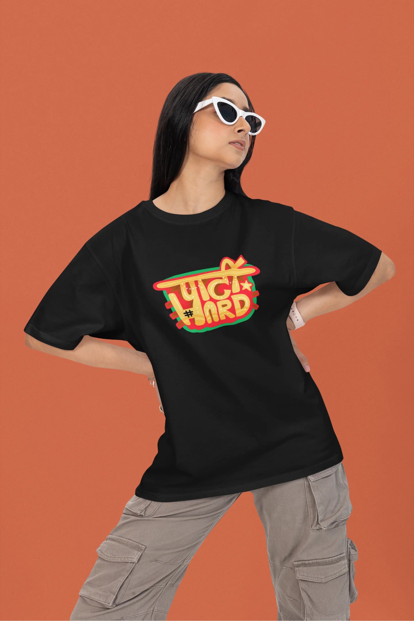 2nd front view of a female model wearing a black oversized t-shirt with the phrase "Party Hard" in an energetic Hindi.