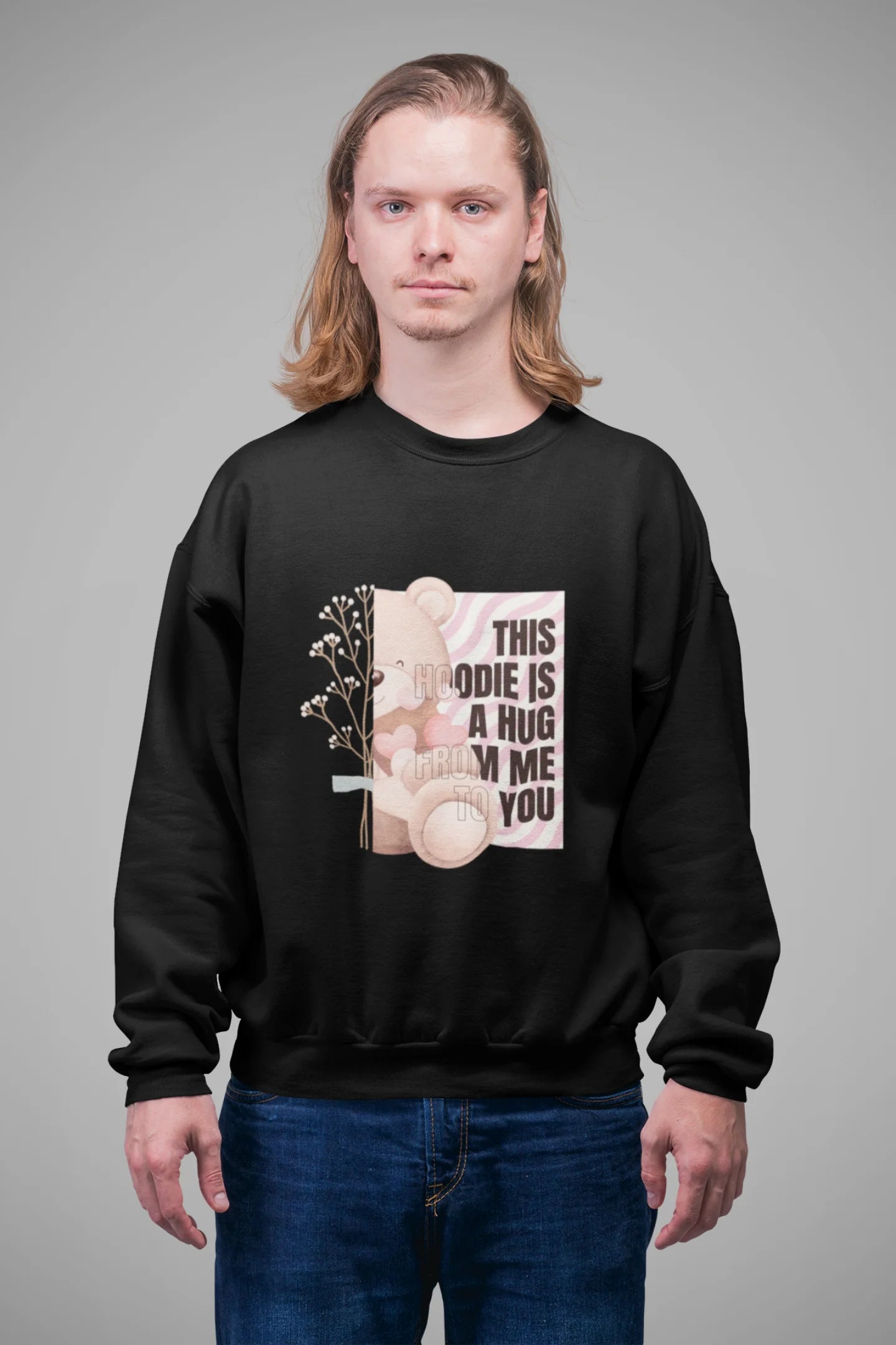4th front view of a male model wearing a black sweatshirt with a heartwarming design of a teddy bear offering a hug, offering a comforting and relaxing aesthetic.