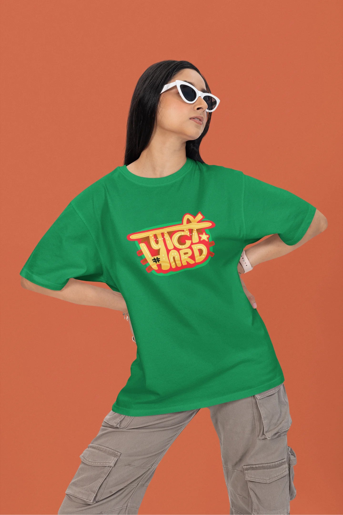 First front view of a female model wearing a forest green oversized t-shirt with the phrase "Party Hard" in an energetic Hindi.