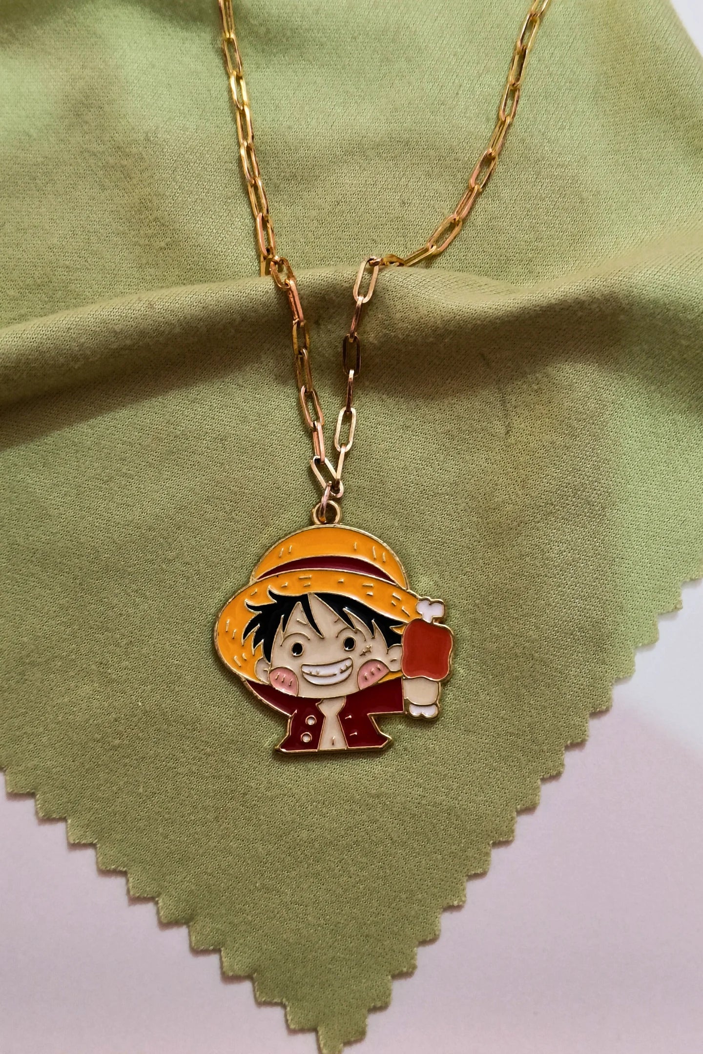2nd view of a gold chain necklace with a small pendant depicting Luffy from One Piece eating meat.