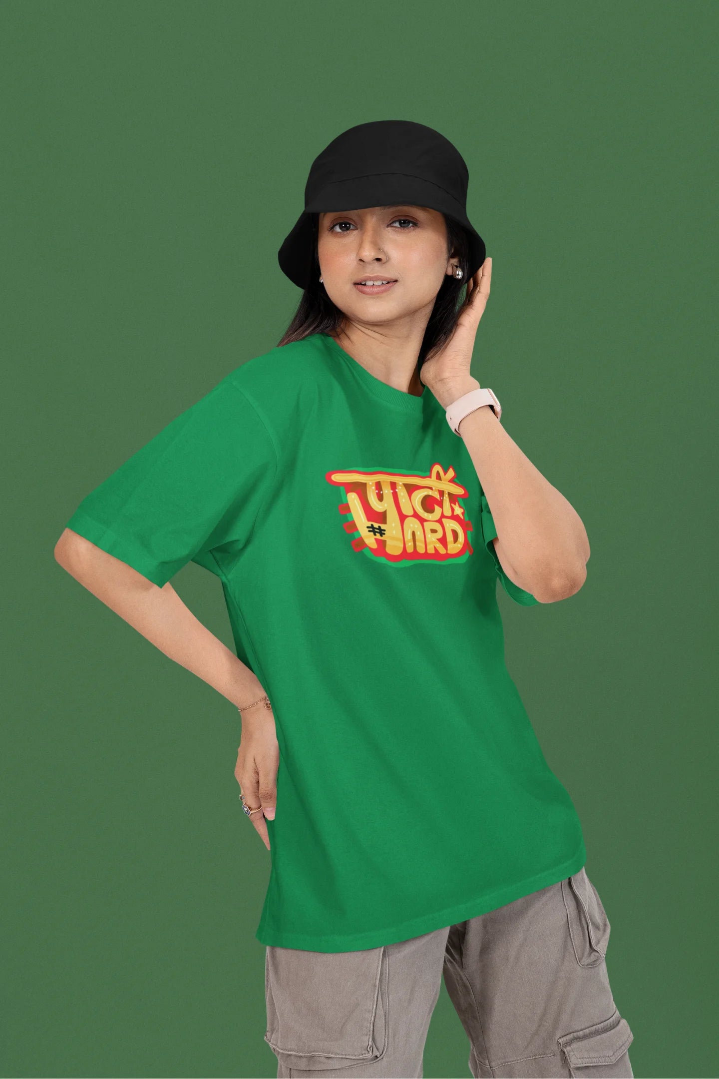 3rd front view of a female model wearing a forest green oversized t-shirt with the phrase "Party Hard" in an energetic Hindi.