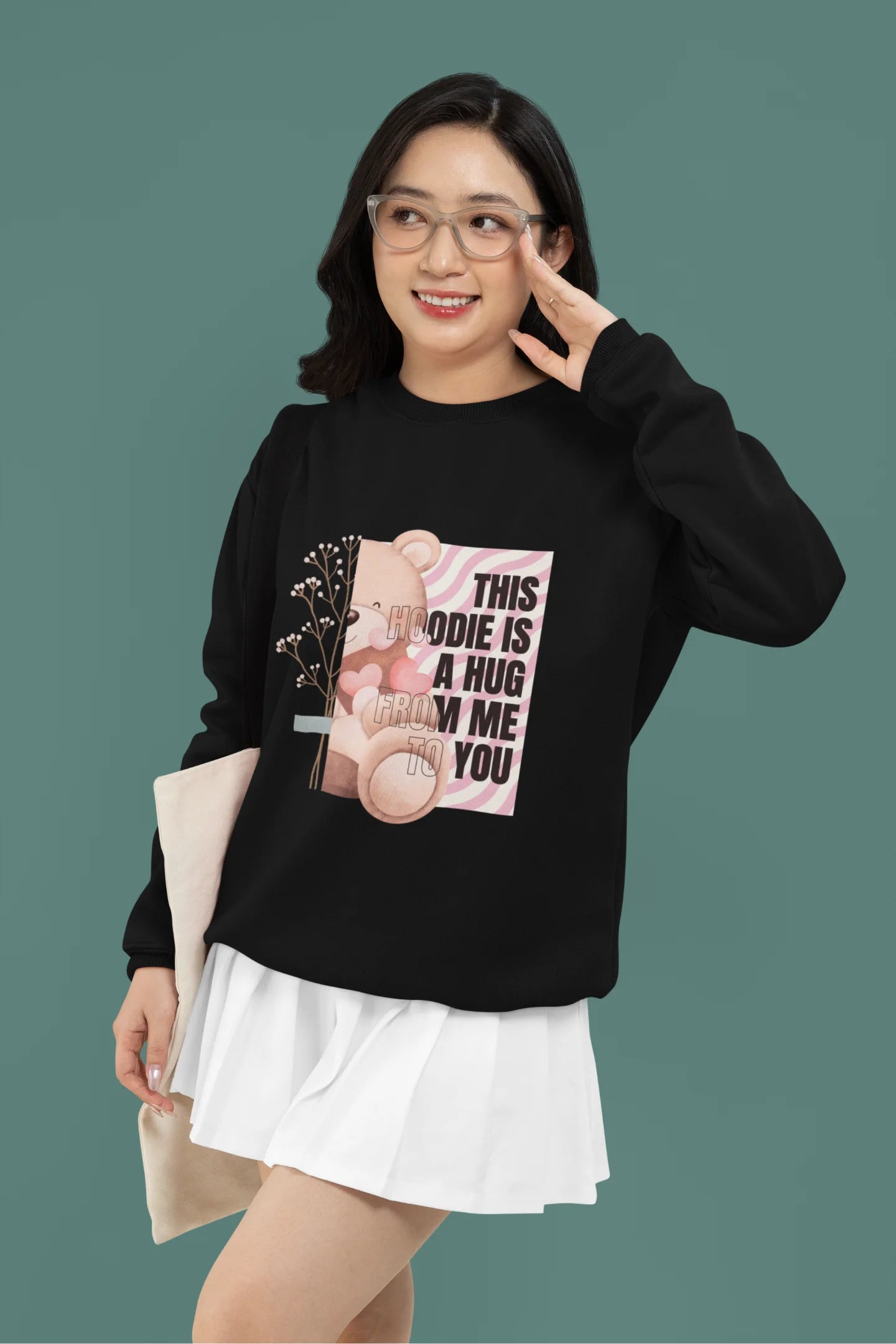 3rd front view of a female model wearing a black sweatshirt with a heartwarming design of a teddy bear offering a hug, offering a comforting and relaxing aesthetic.