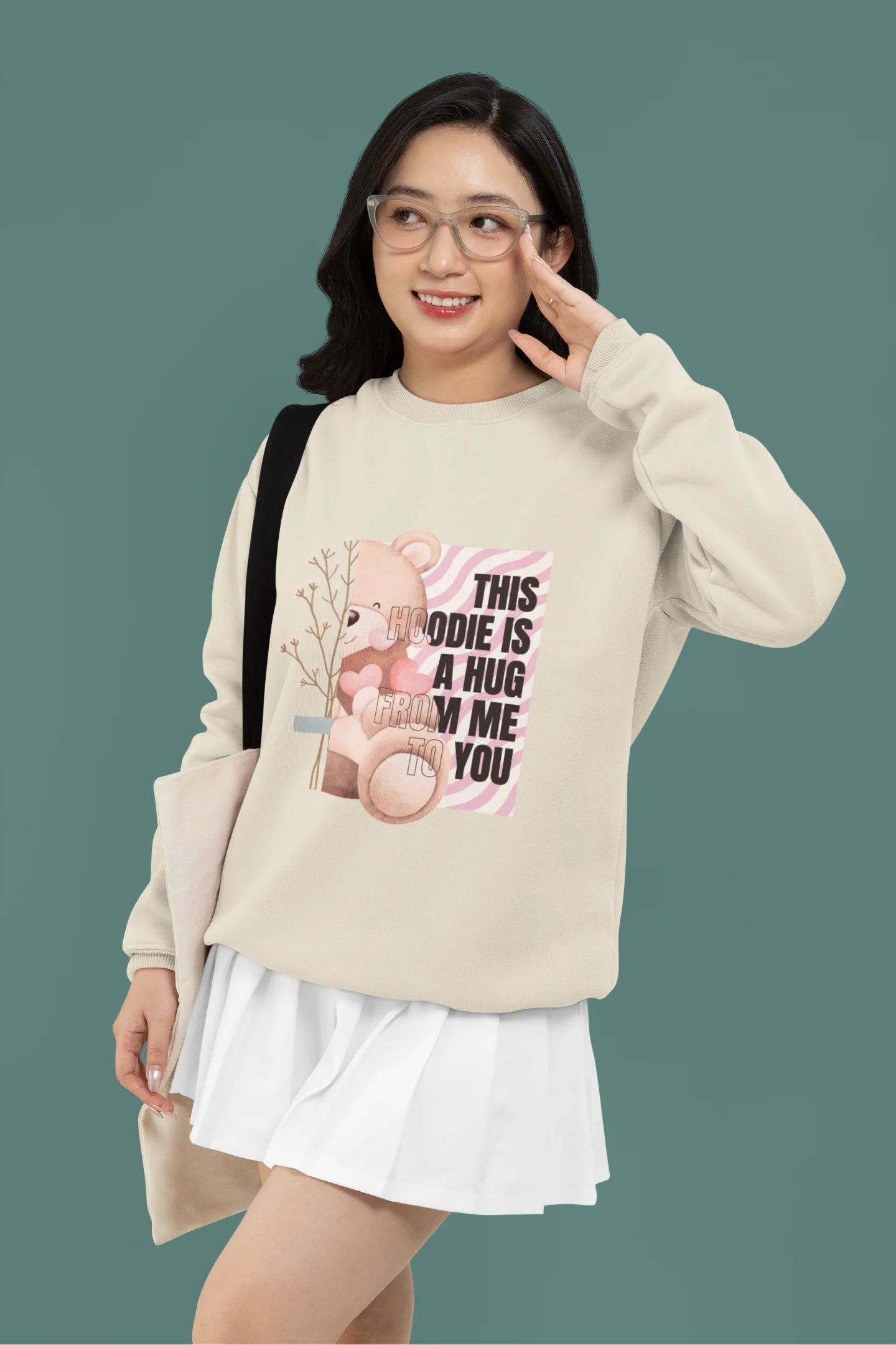 4th front view of a female model wearing a cream sweatshirt with a heartwarming design of a teddy bear offering a hug, offering a comforting and relaxing aesthetic.