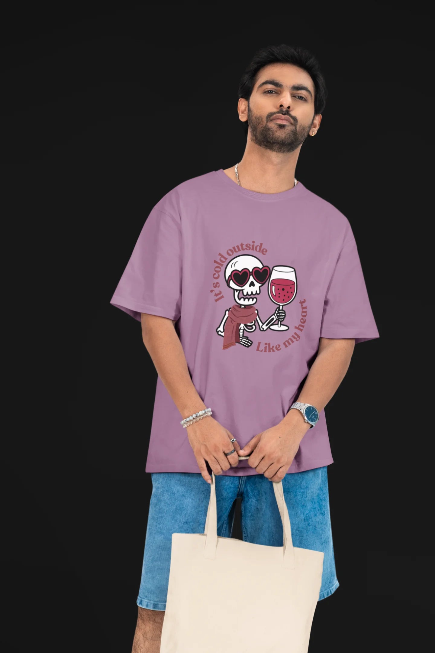 First front image of a male model wearing a dirty purple oversized t-shirt with the text "Cold Outside Like My Heart" and a design of a skeleton drinking champagne.