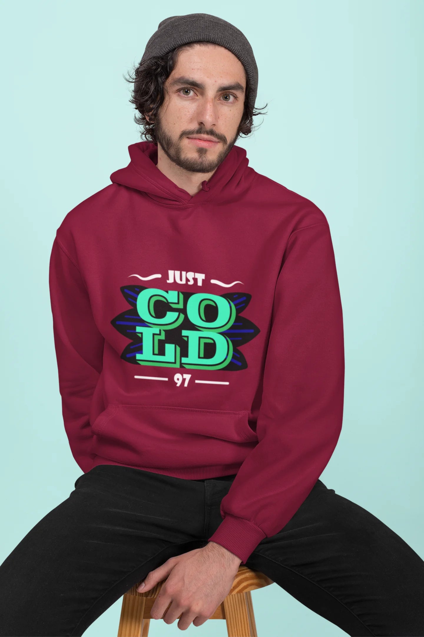 2nd front view of a male model wearing an maroon sweatshirt with the text "Just Cold" printed on it.