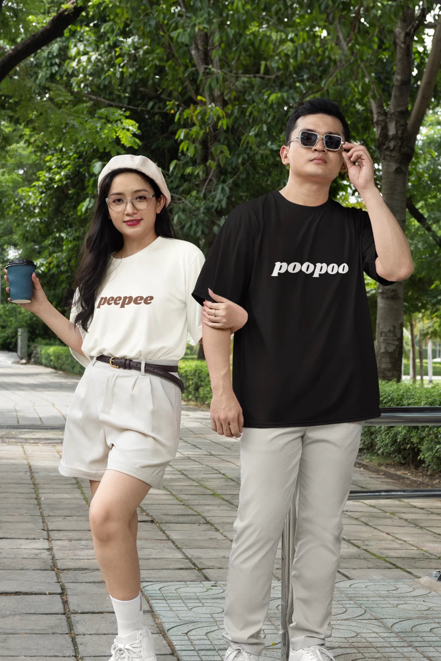 3rd front view of a couple wearing matching black and white oversize tees, one with the word "PeePee" and the other with the word "PooPoo".