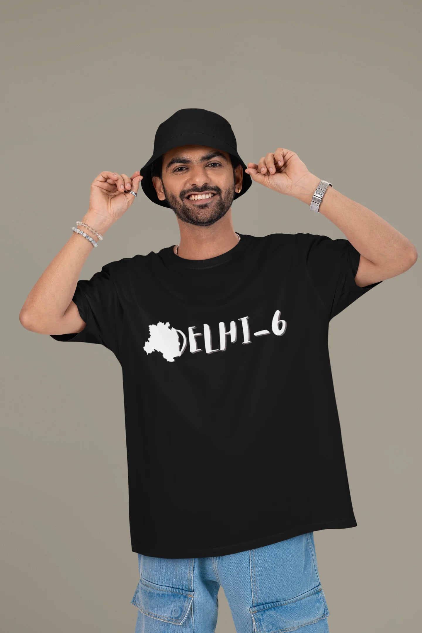 Front view of a male model wearing a black oversized t-shirt featuring a design incorporating the Red Fort and elements representing the city of Delhi, inspired by the Hindi film Delhi 6.