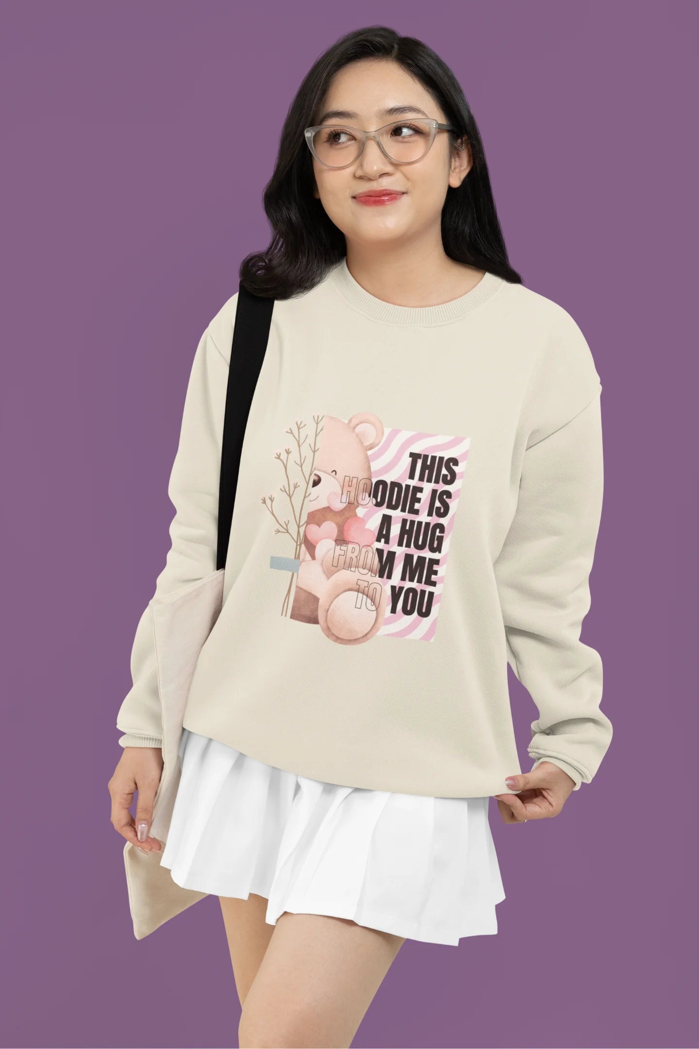 First front view of a female model wearing a cream sweatshirt with a heartwarming design of a teddy bear offering a hug, offering a comforting and relaxing aesthetic.